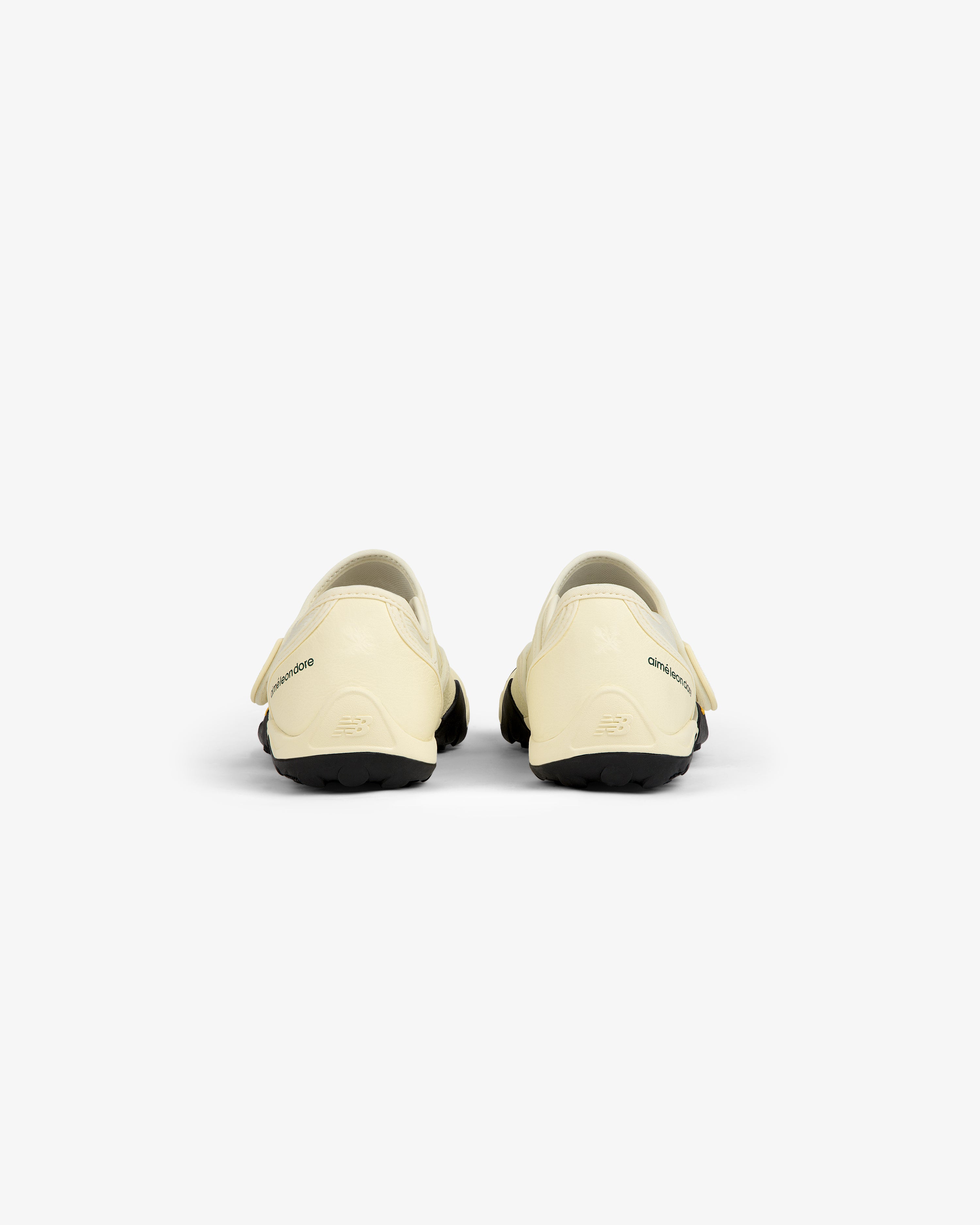 Back view of two cream-colored ALD / New Balance MT2 slip-on shoes with black lugged soles.