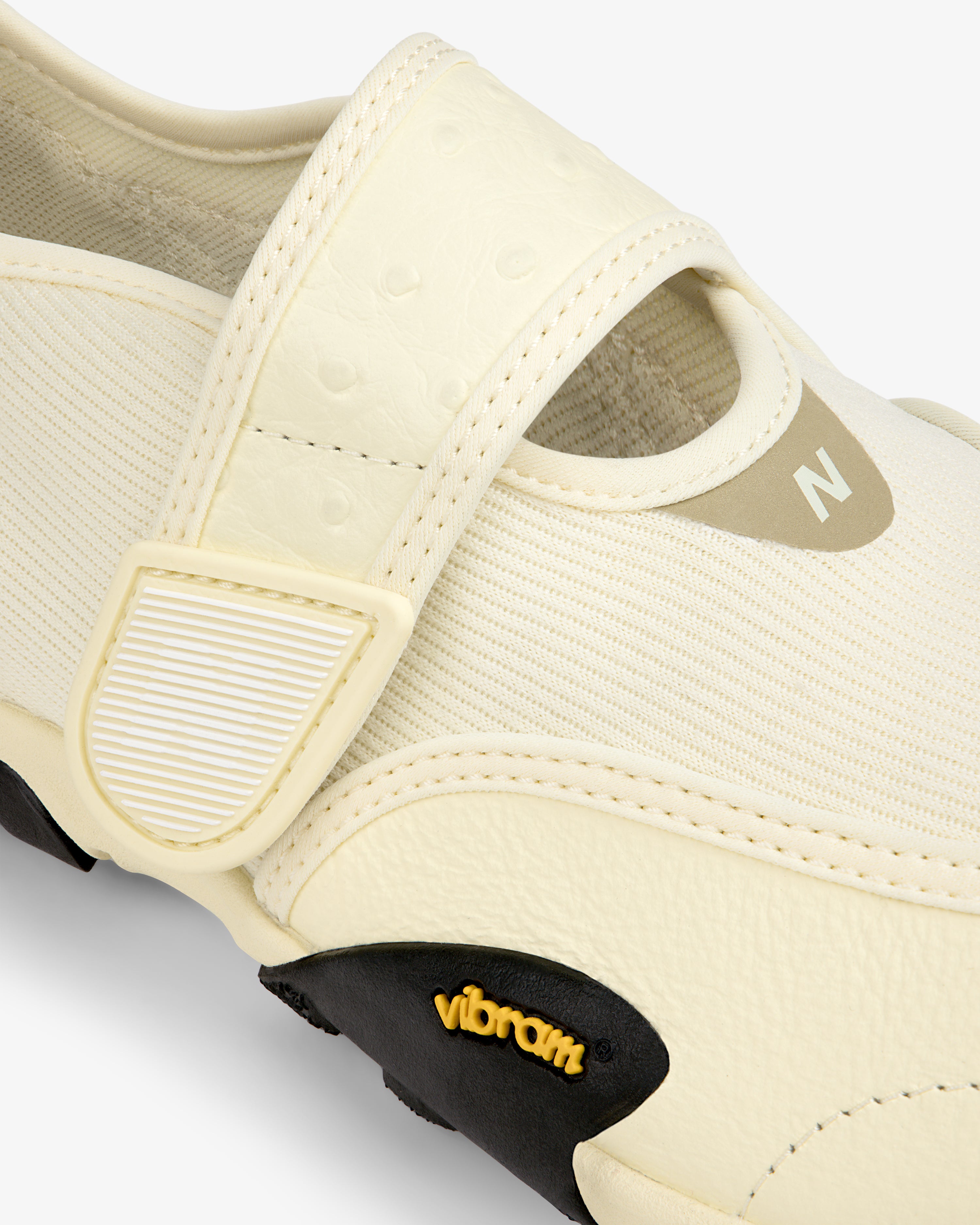 Close-up of a cream-colored ALD / New Balance MT2 slip-on shoe with a hook-and-loop strap and a black Vibram outsole.