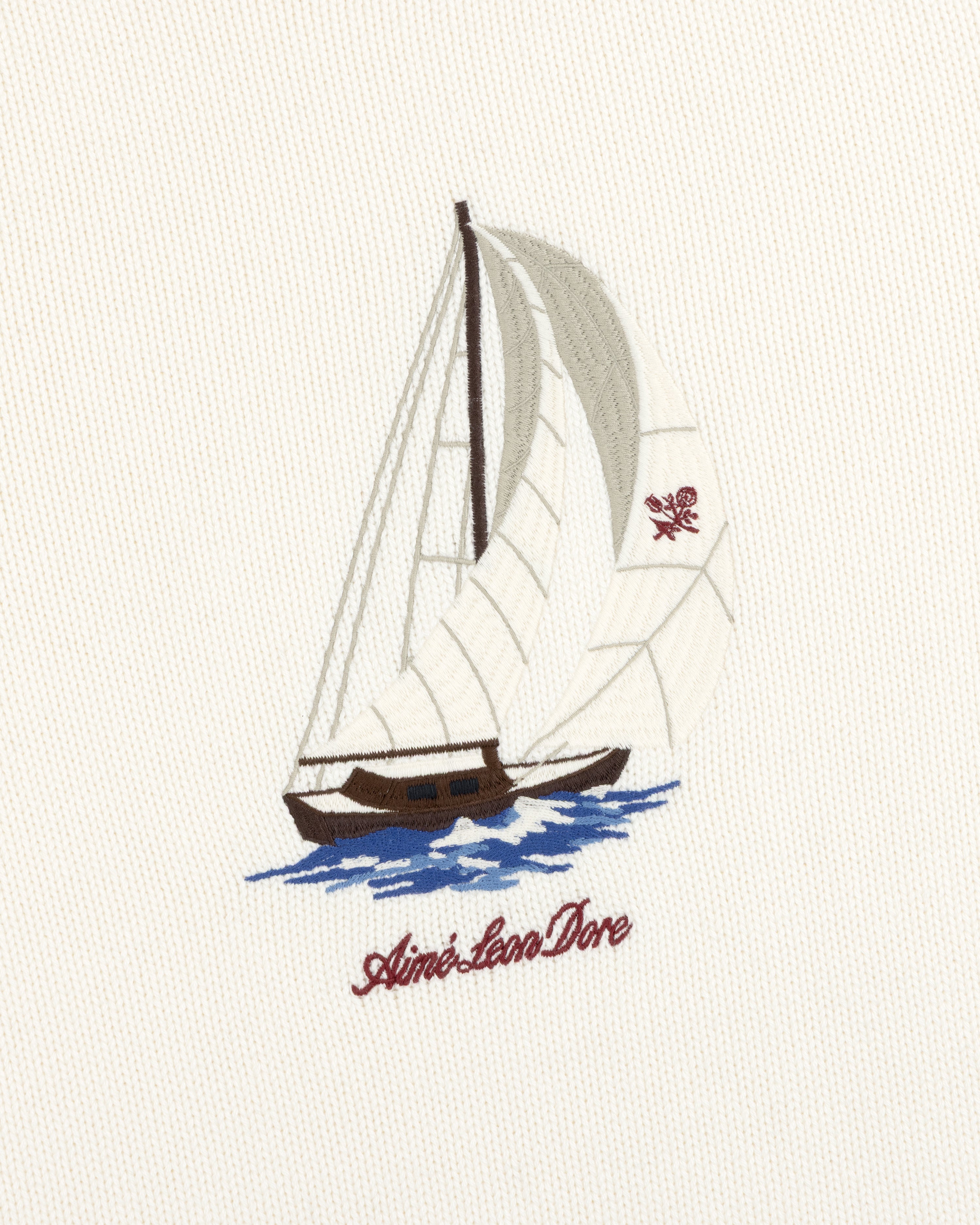 Regatta Embroidered Crewneck Sweater with a sailboat design and Aimé Leon Dore in red script underneath.