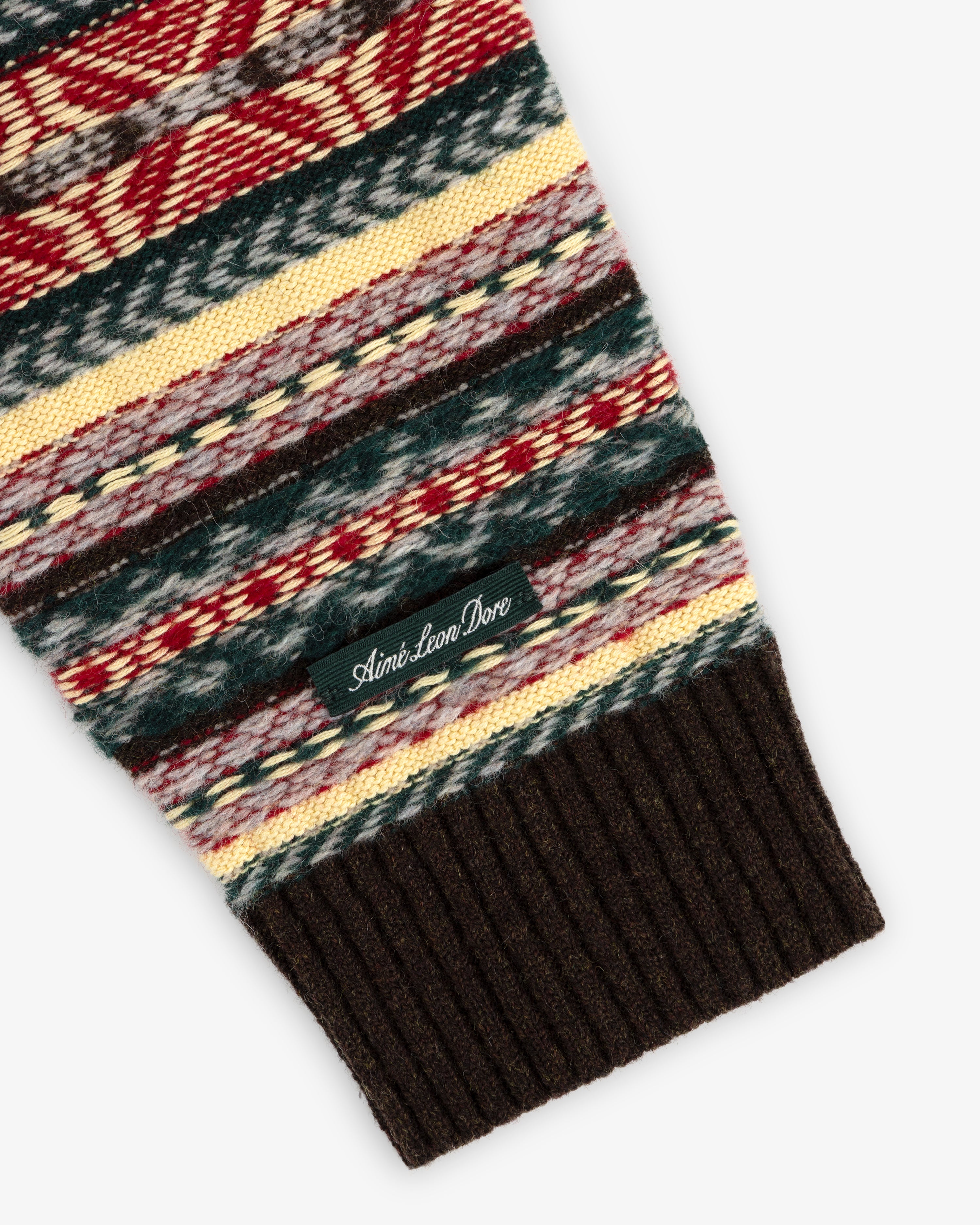 Fair Isle V-Neck Sweater sleeve features multicolor patterns, ribbed brown cuff, and a small Aimé Leon Dore tag.