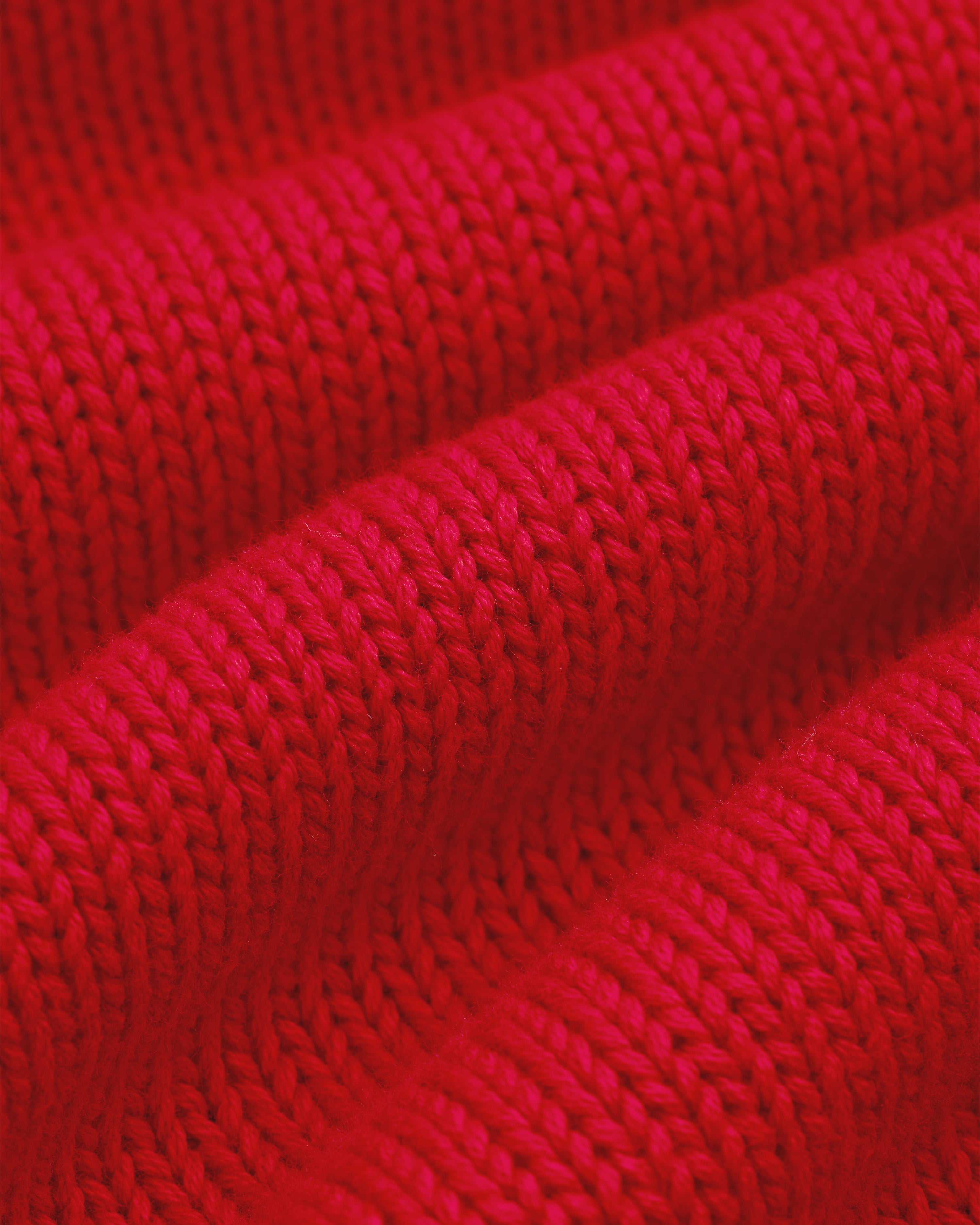 Close-up of Crest Raglan Sweater showing bright red ribbed knit and evenly spaced stitch rows.