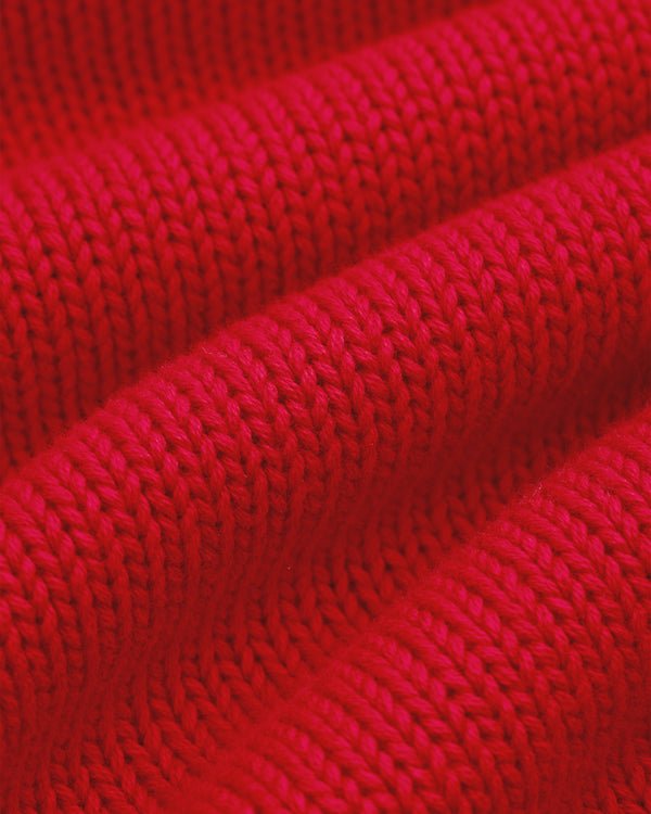 Close-up of Crest Raglan Sweater showing bright red ribbed knit and evenly spaced stitch rows.