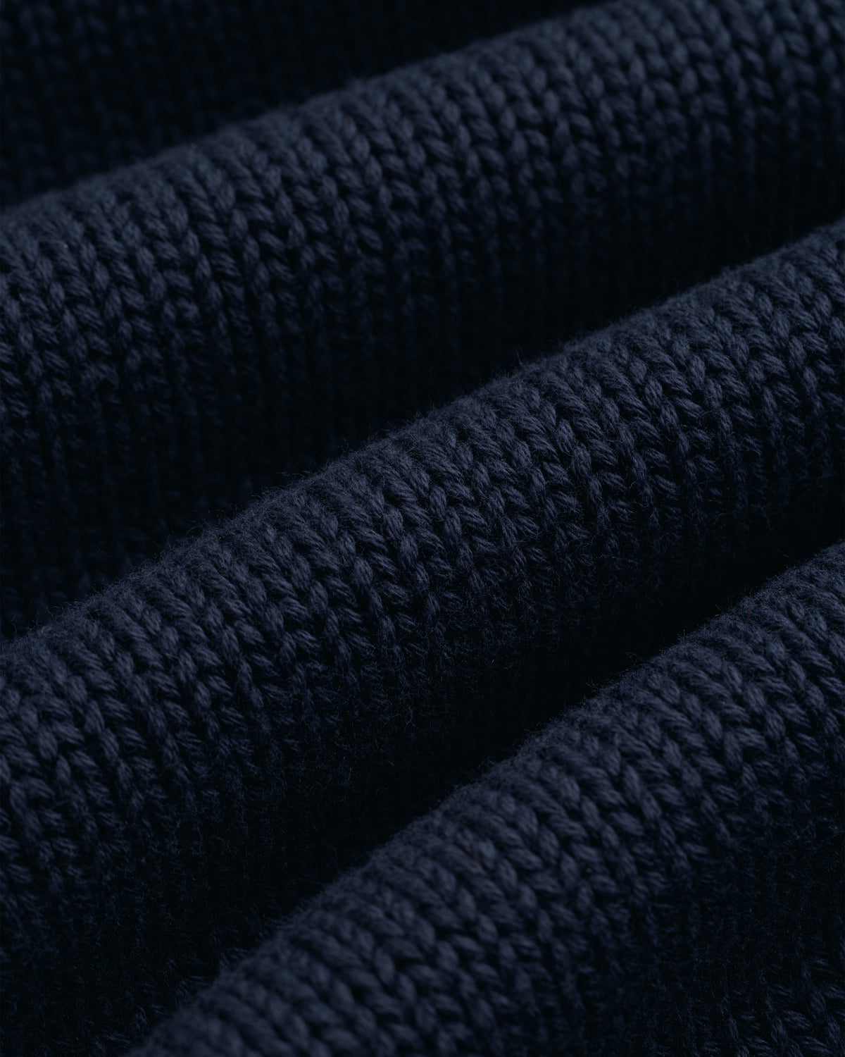 Close-up of the Crest Raglan Sweater’s dark blue ribbed knit, featuring soft horizontal ridges and even stitching.