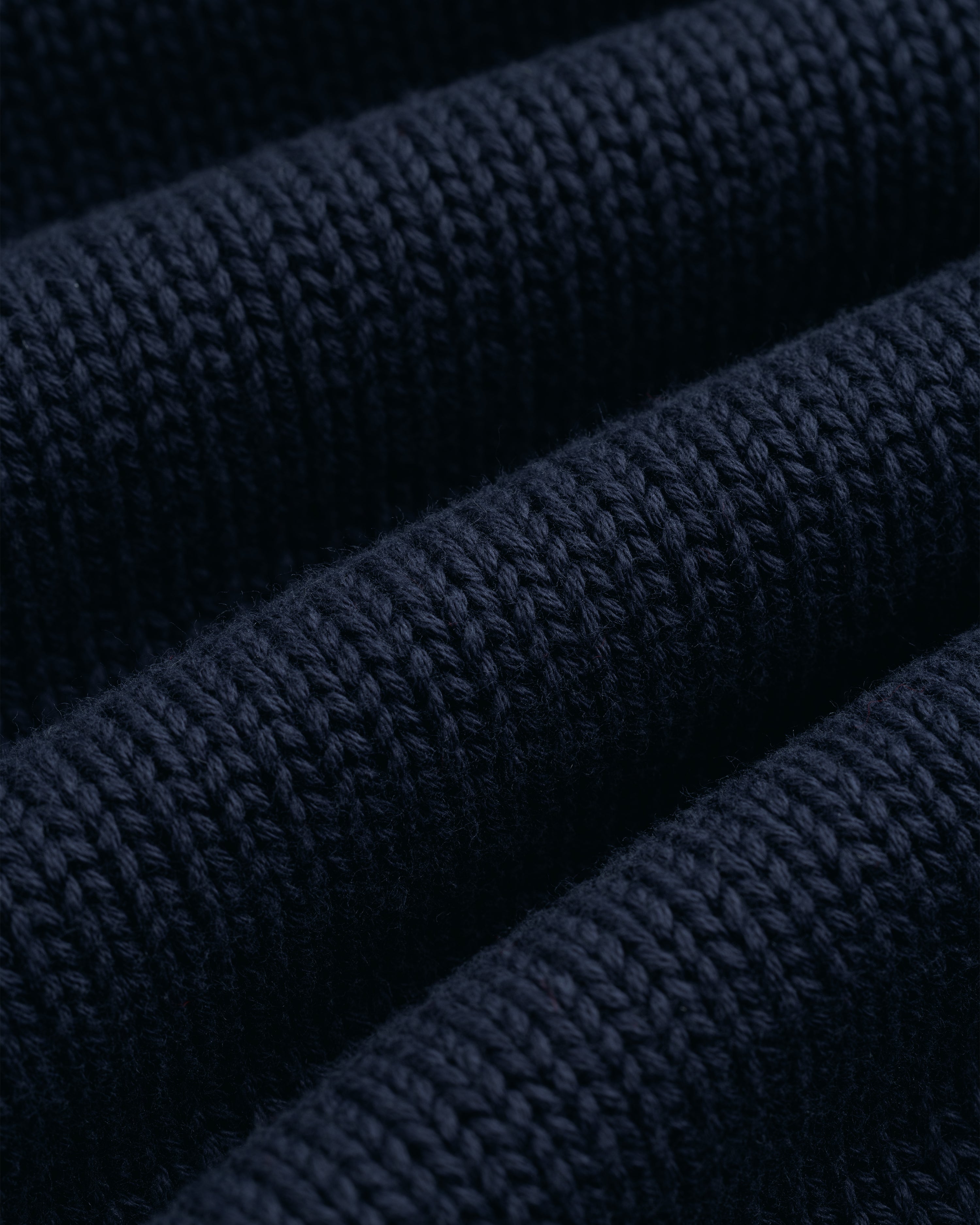 Close-up of the Crest Raglan Sweater’s dark blue ribbed knit, featuring soft horizontal ridges and even stitching.