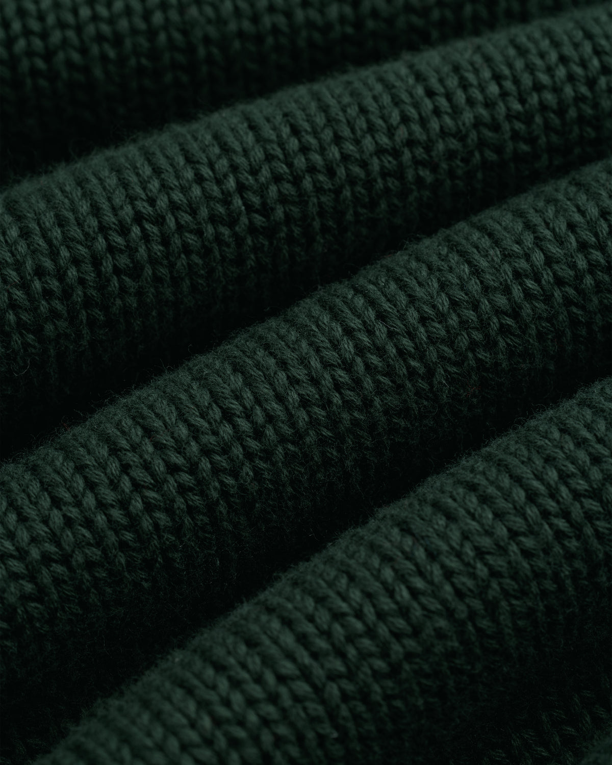 Close-up of Crest Raglan Sweater in dark green with horizontal ribbed texture and plush, thick yarn.