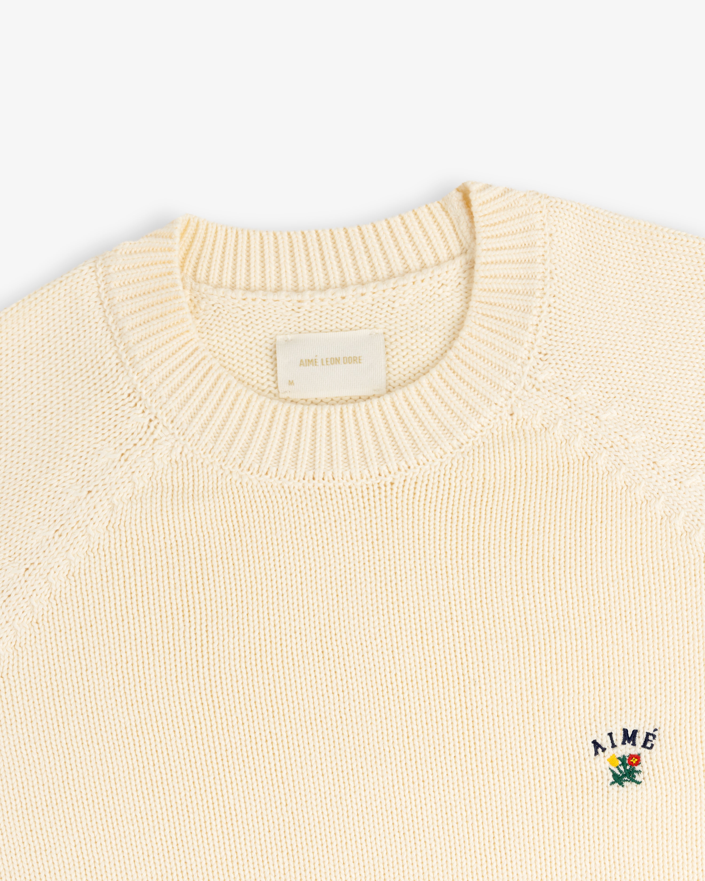 Crest Raglan Sweater: Cream knit with ribbed collar, small flower AIME logo embroidered on the chest.
