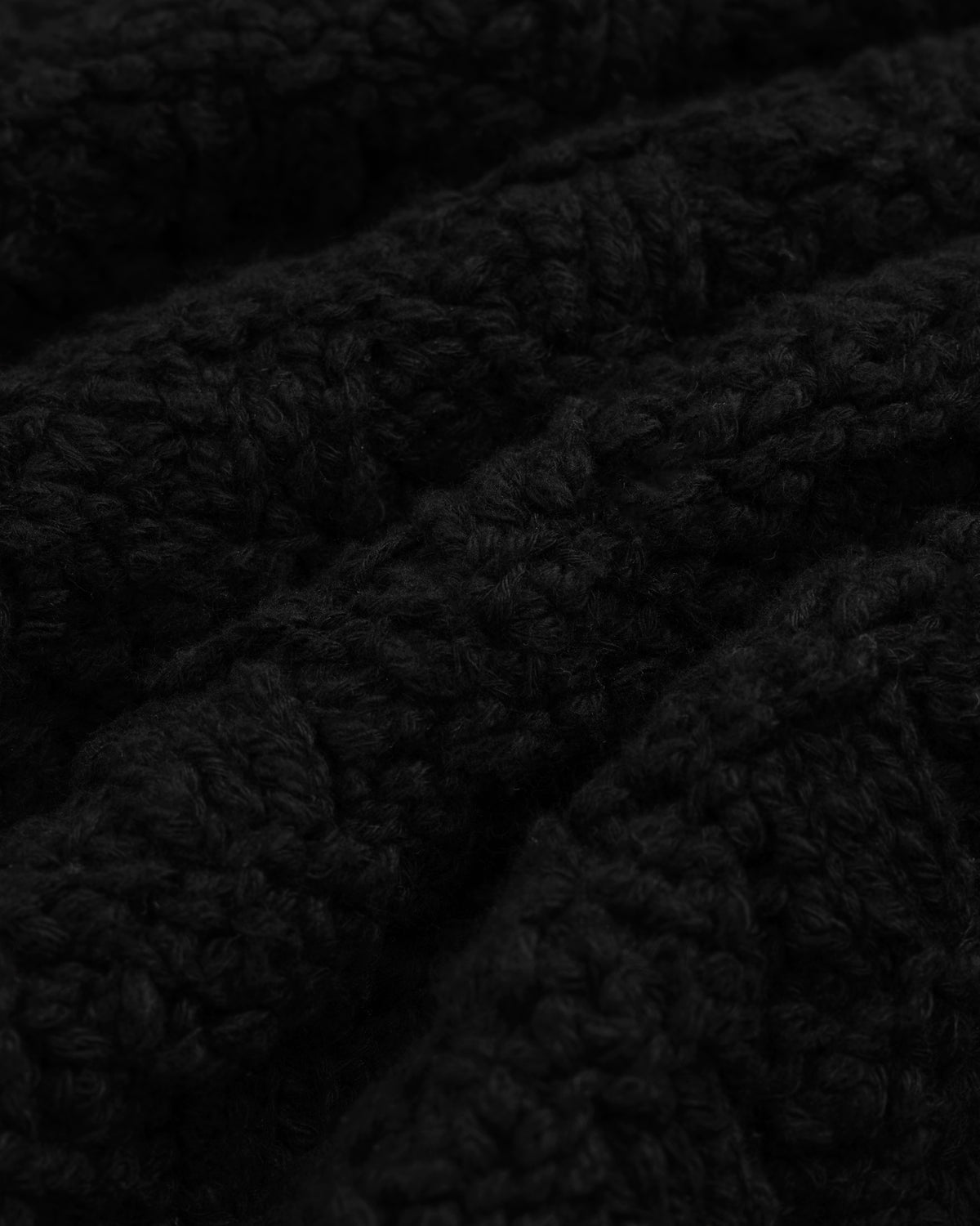 Close-up of a Checkerboard Bouclé Sweater in black textured knit with a subtle checkerboard pattern.