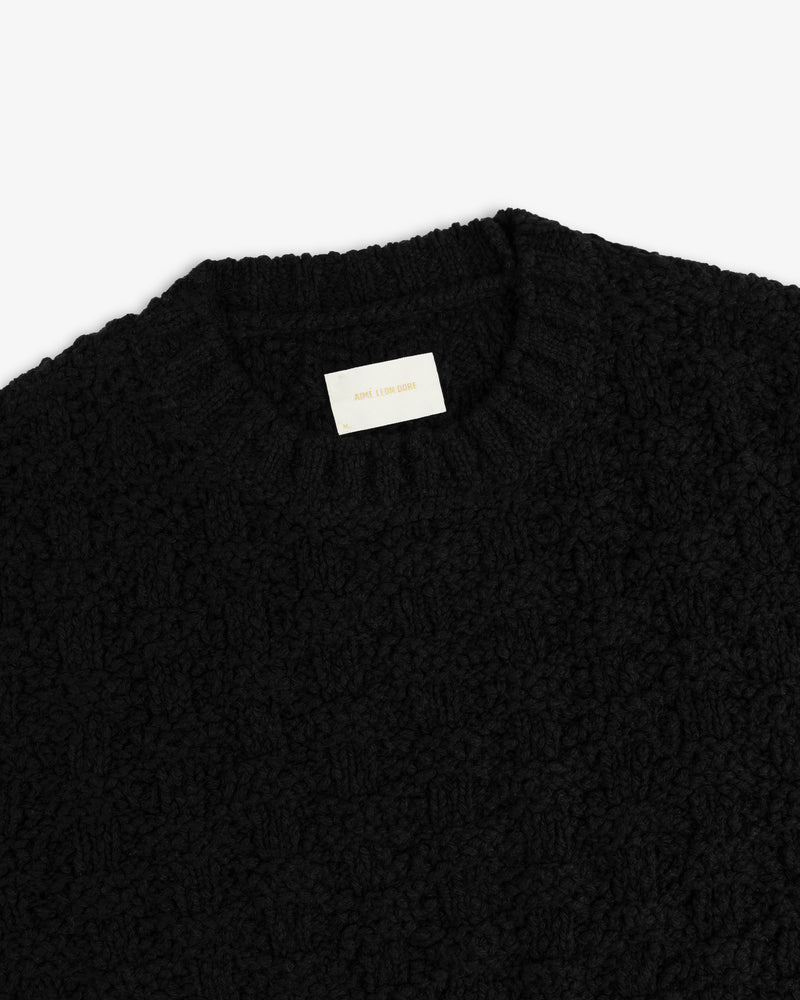Black Checkerboard Bouclé Sweater with a textured, bumpy knit and a branded collar tag.