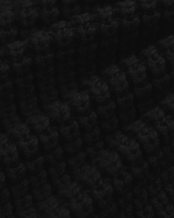 Close-up of the thick, black ribbed knit fabric of a Merino Wool Full Zip Sweater.