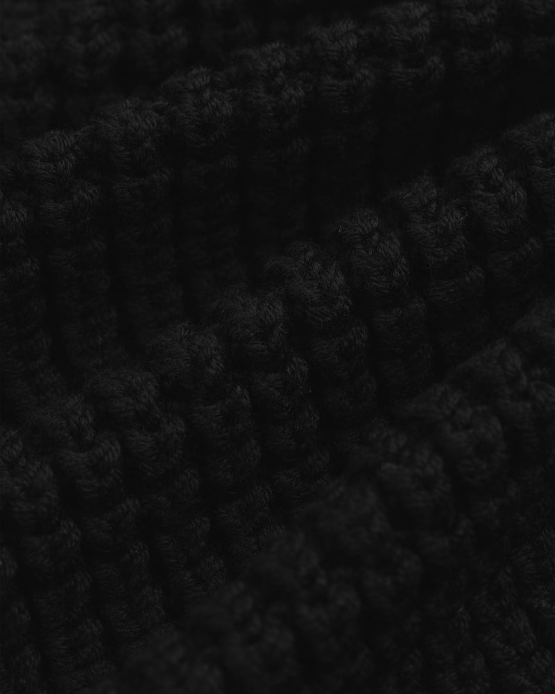 Close-up of the thick, black ribbed knit fabric of a Merino Wool Full Zip Sweater.