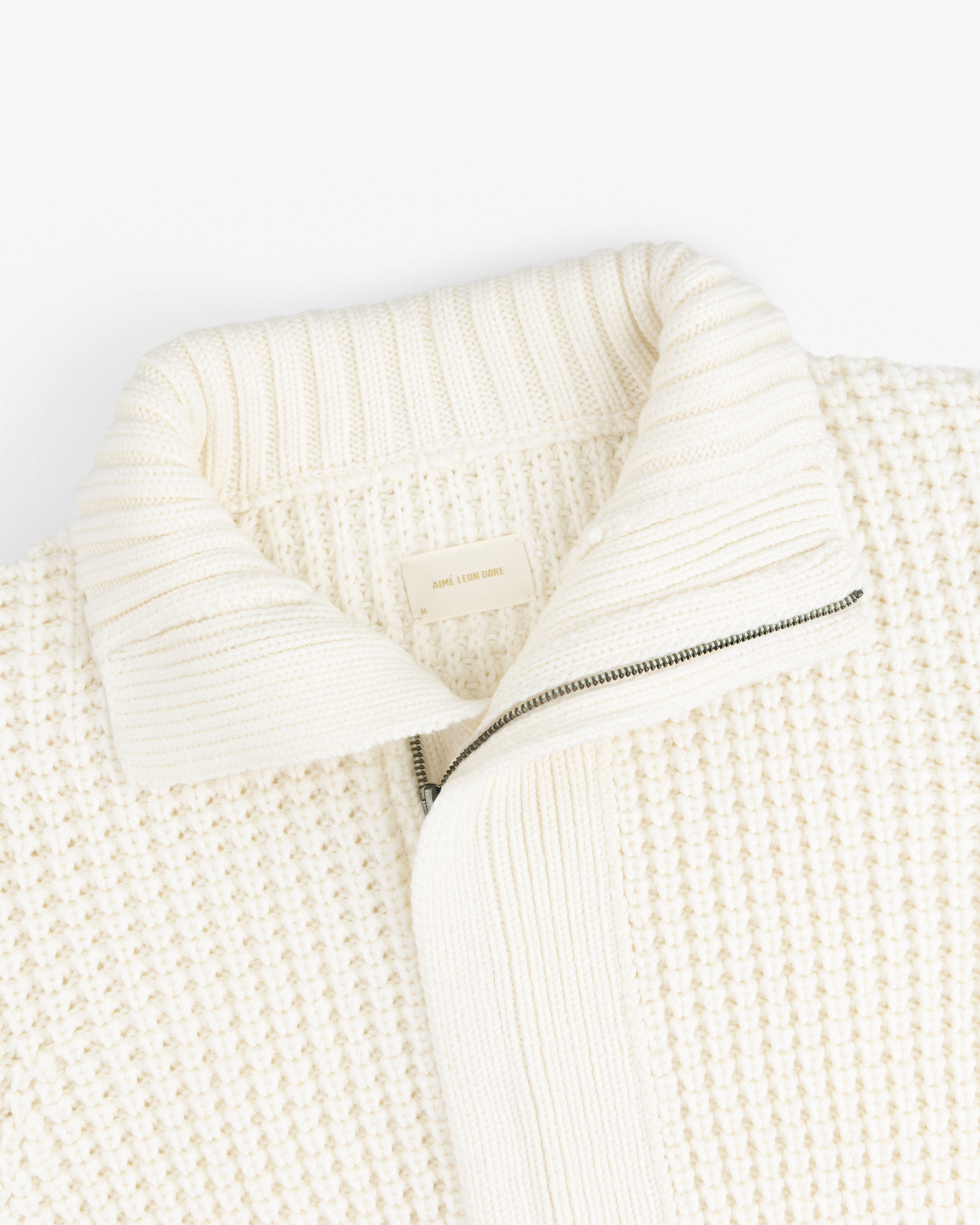 Cream-colored Merino Wool Full Zip Sweater with a ribbed collar and a partial zipper.
