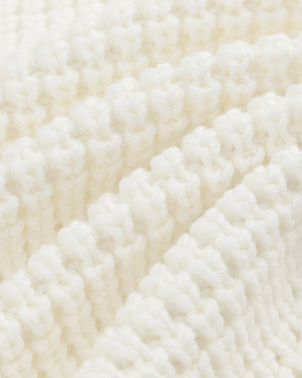 Close-up of white ribbed knit fabric on a Merino Wool Full Zip Sweater, shown with diagonal folds.