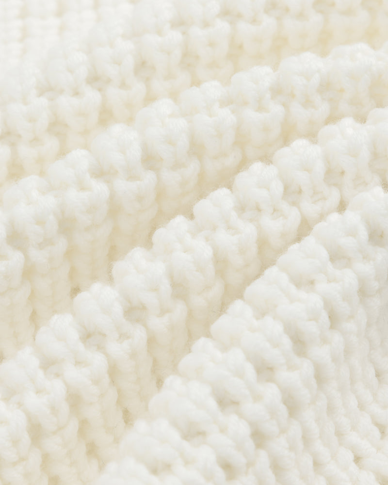 Close-up of white ribbed knit fabric on a Merino Wool Full Zip Sweater, shown with diagonal folds.