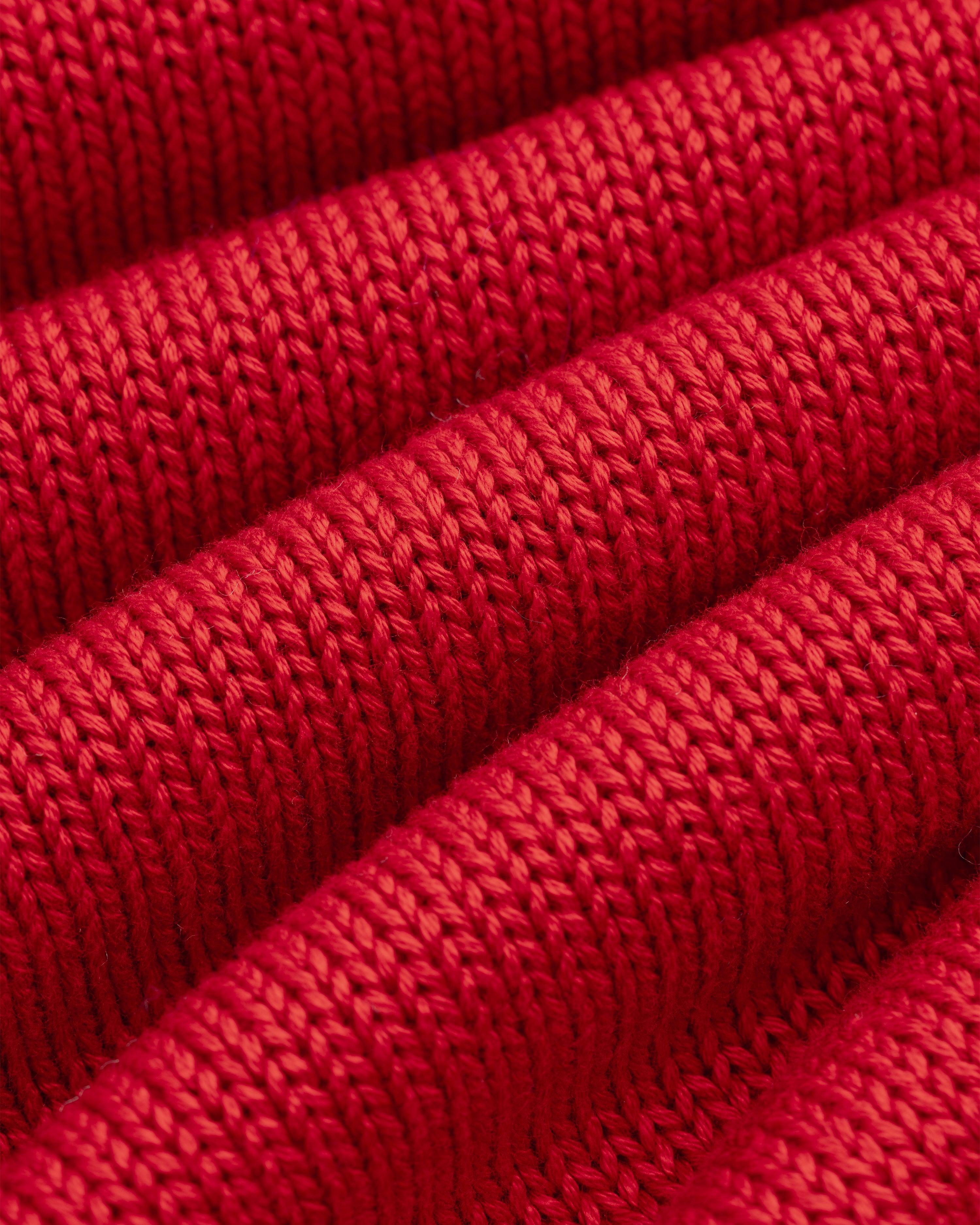 Close-up of red knit fabric with diagonal ridges on a Knit Pocket Crewneck Sweater.