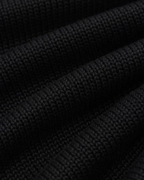 Close-up of black Knit Pocket Crewneck Sweater fabric featuring deep, horizontal folds.