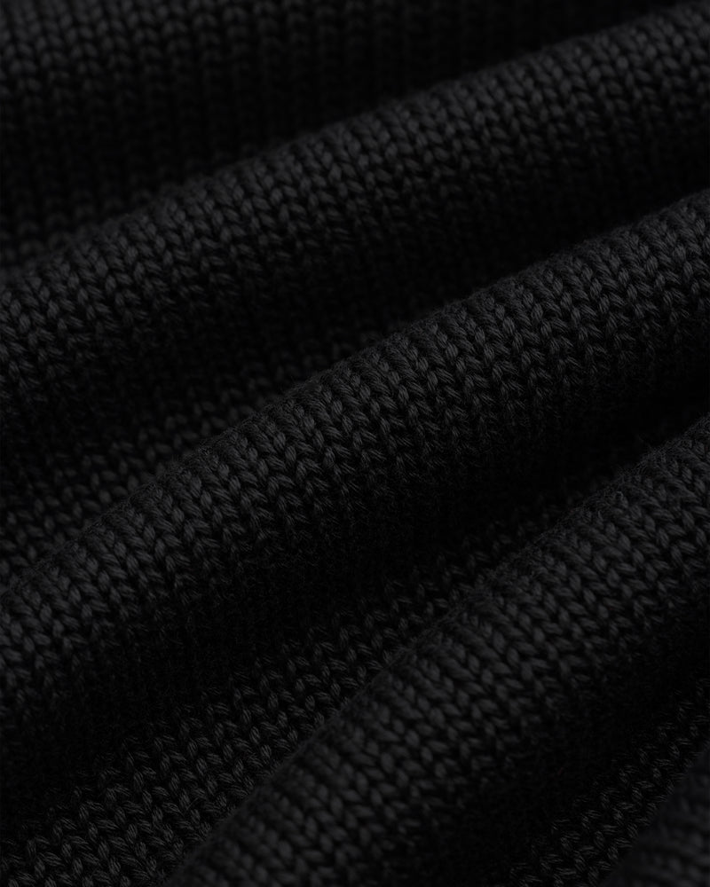 Close-up of black Knit Pocket Crewneck Sweater fabric featuring deep, horizontal folds.