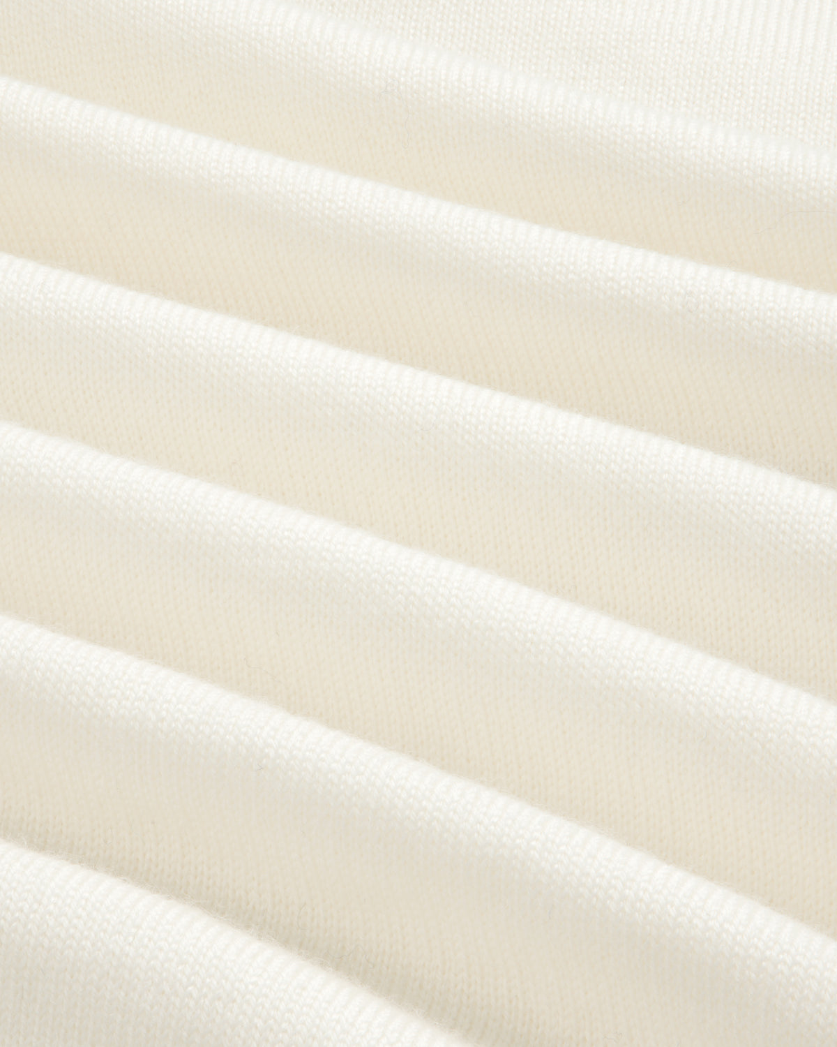 Close-up of soft, white Merino Wool Knit Cycling Polo with horizontal, evenly spaced ribbed texture.