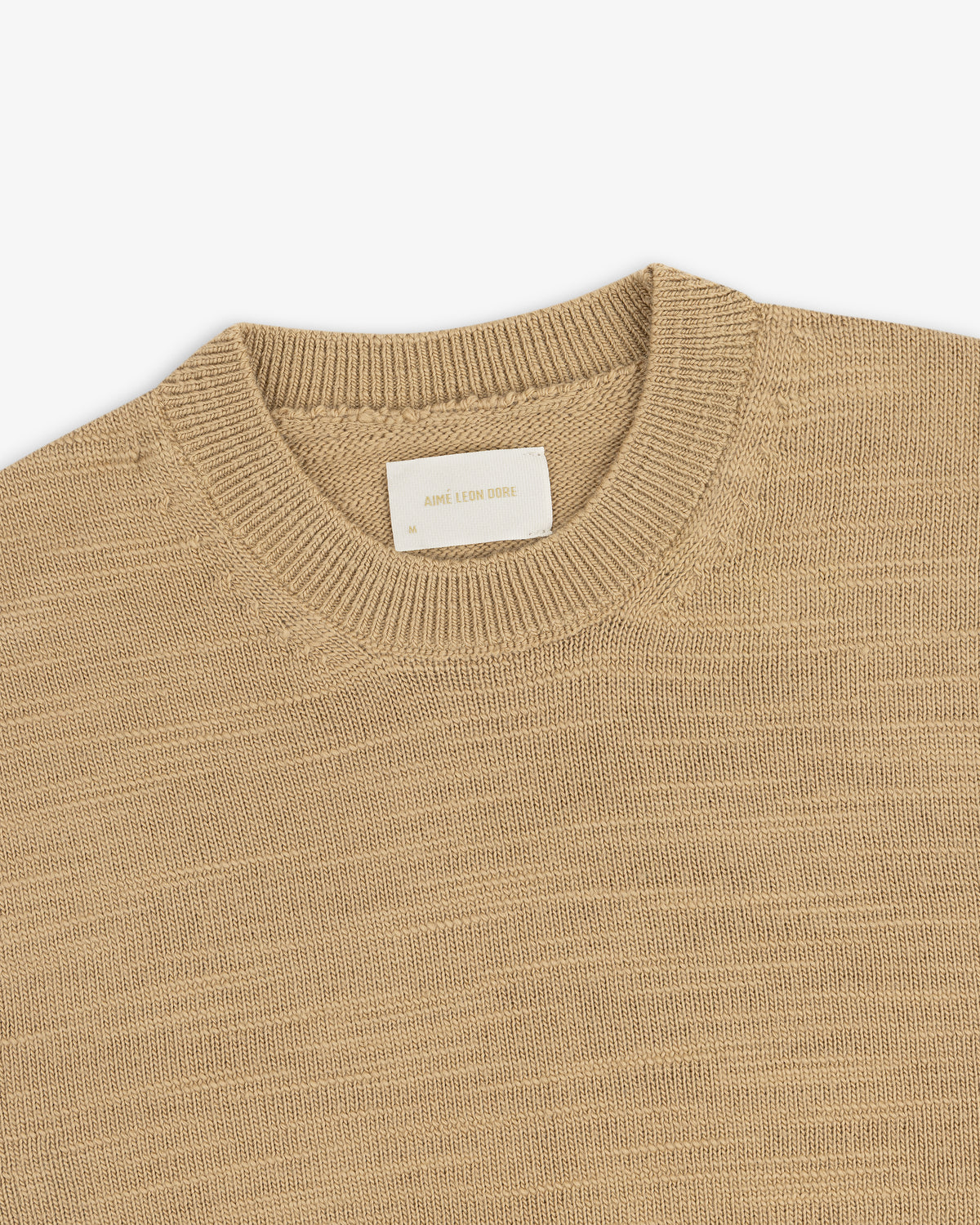 Tan Slub Merino Wool sweater with a ribbed collar and a size medium clothing tag.
