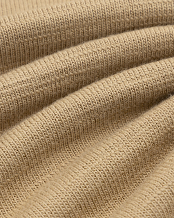 Close-up of the Slub Merino Wool Sweater in tan knit fabric with visible folds.