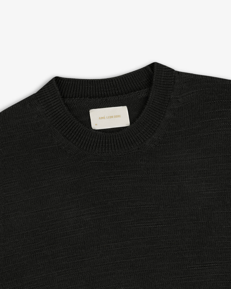 Black Slub Merino Wool sweater with a ribbed crewneck collar and a branded neck label.