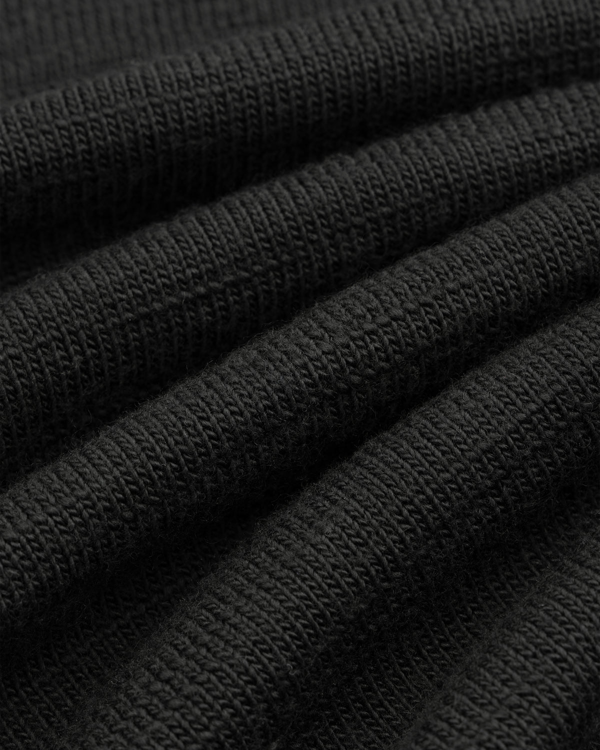 Close-up of the black Slub Merino Wool Sweater, showing its visible knit texture.