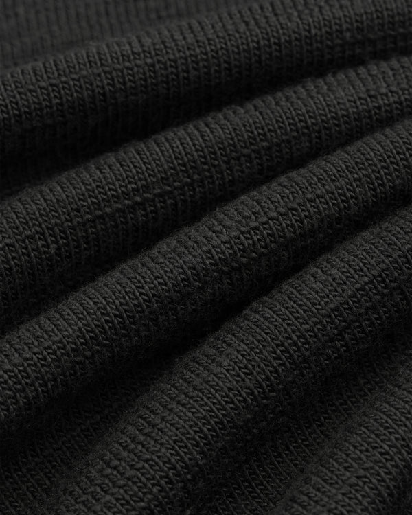 Close-up of the black Slub Merino Wool Sweater, showing its visible knit texture.