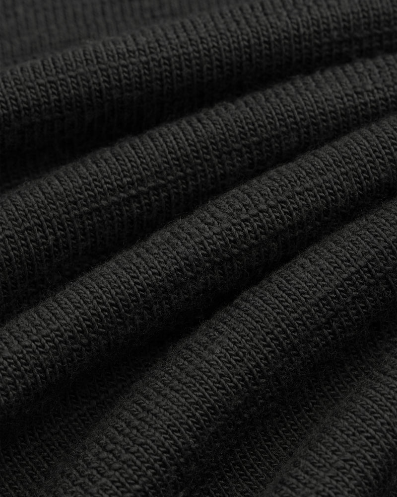 Close-up of the black Slub Merino Wool Sweater, showing its visible knit texture.