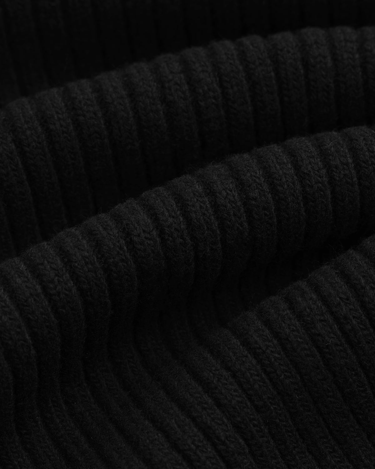 Close-up of a black Wool Ribbed Knit Hoodie featuring a vertical ribbed knit texture.