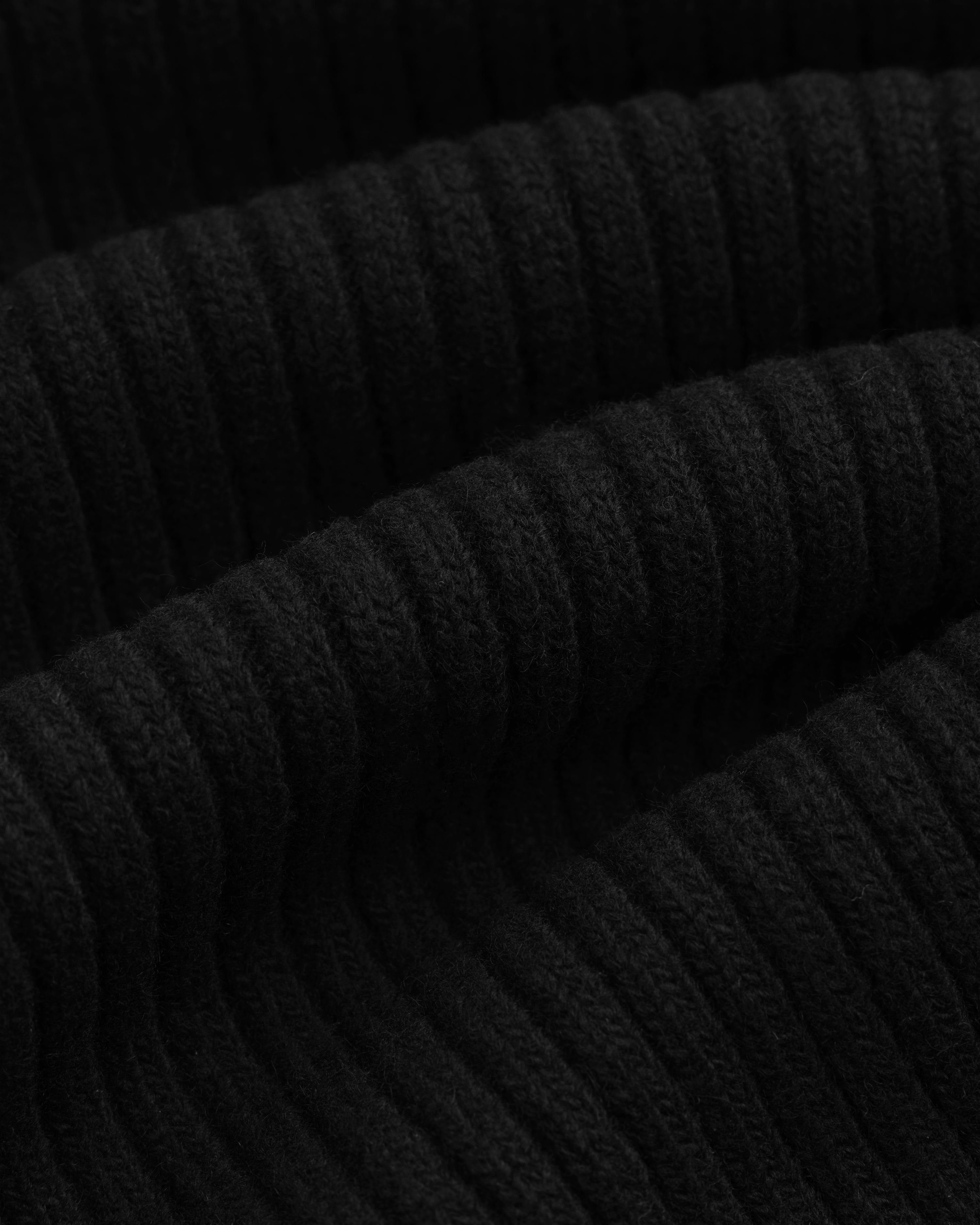 Close-up of a black Wool Ribbed Knit Hoodie featuring a vertical ribbed knit texture.