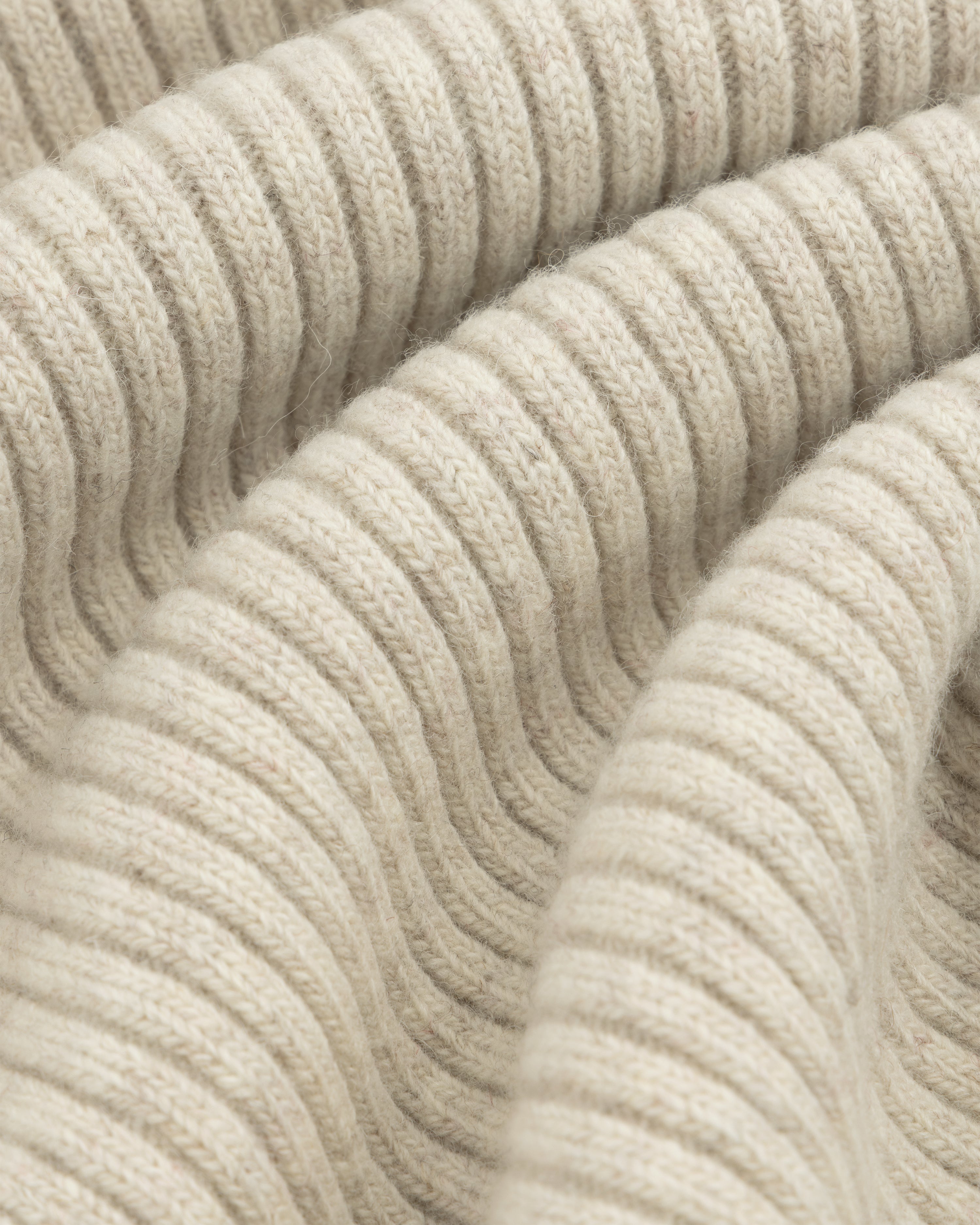 Close-up of beige Wool Ribbed Knit Hoodie fabric with soft folds.