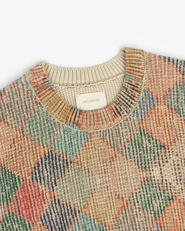 Kilim Argyle Crewneck Sweater with a multicolored argyle pattern, ribbed collar, and Aimé Leon Dore label.
