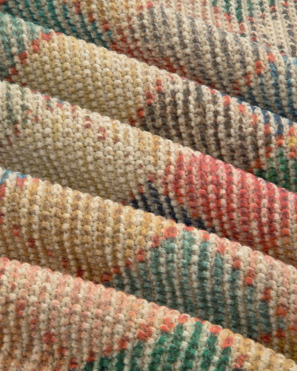 Close-up of Kilim Argyle Crewneck Sweater, folded, showing multicolored stripes in yellow, pink, green, and beige.