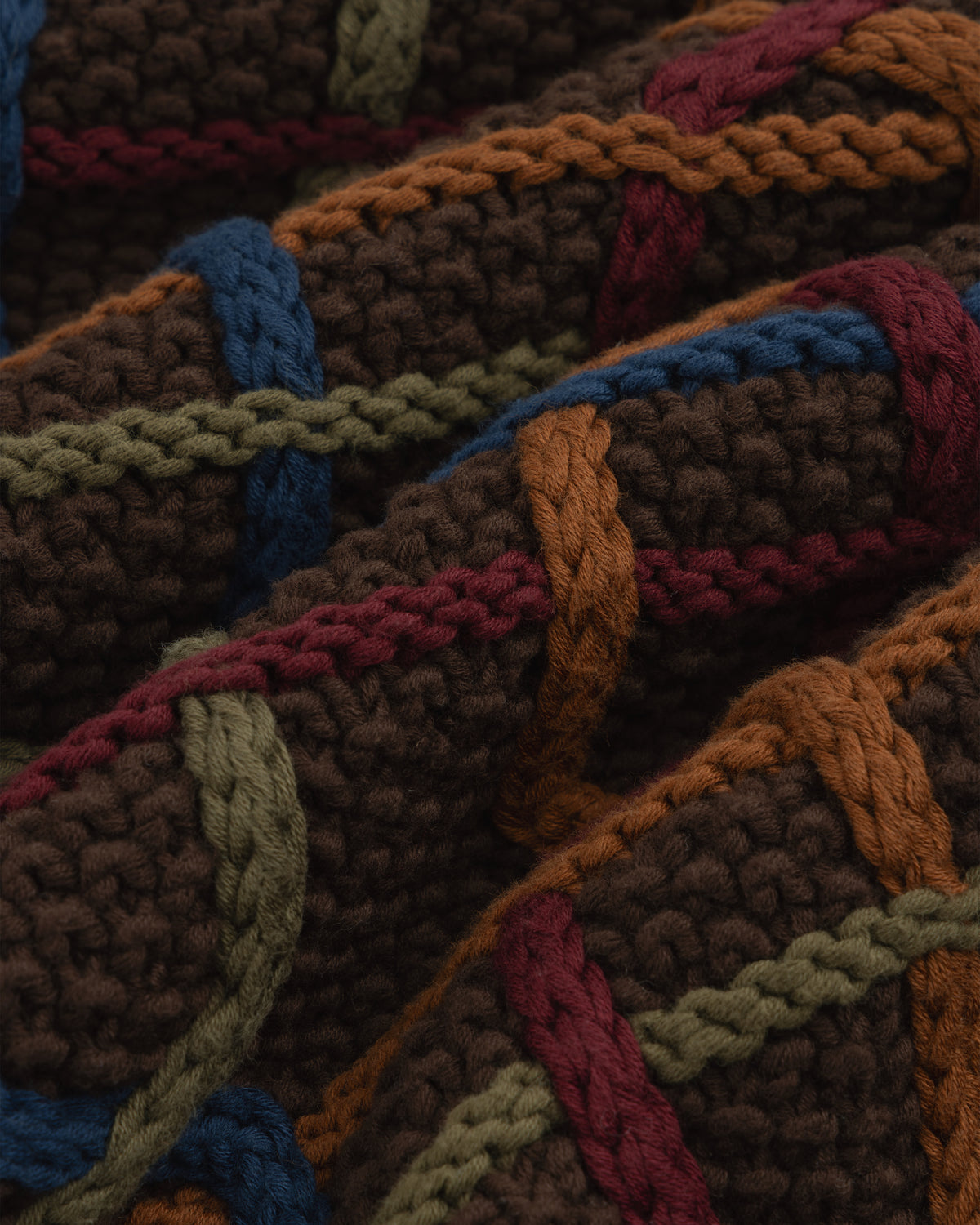 Close-up of a Cable Link Crewneck Sweater in brown with a multicolored cable pattern in blue, green, orange, and maroon.