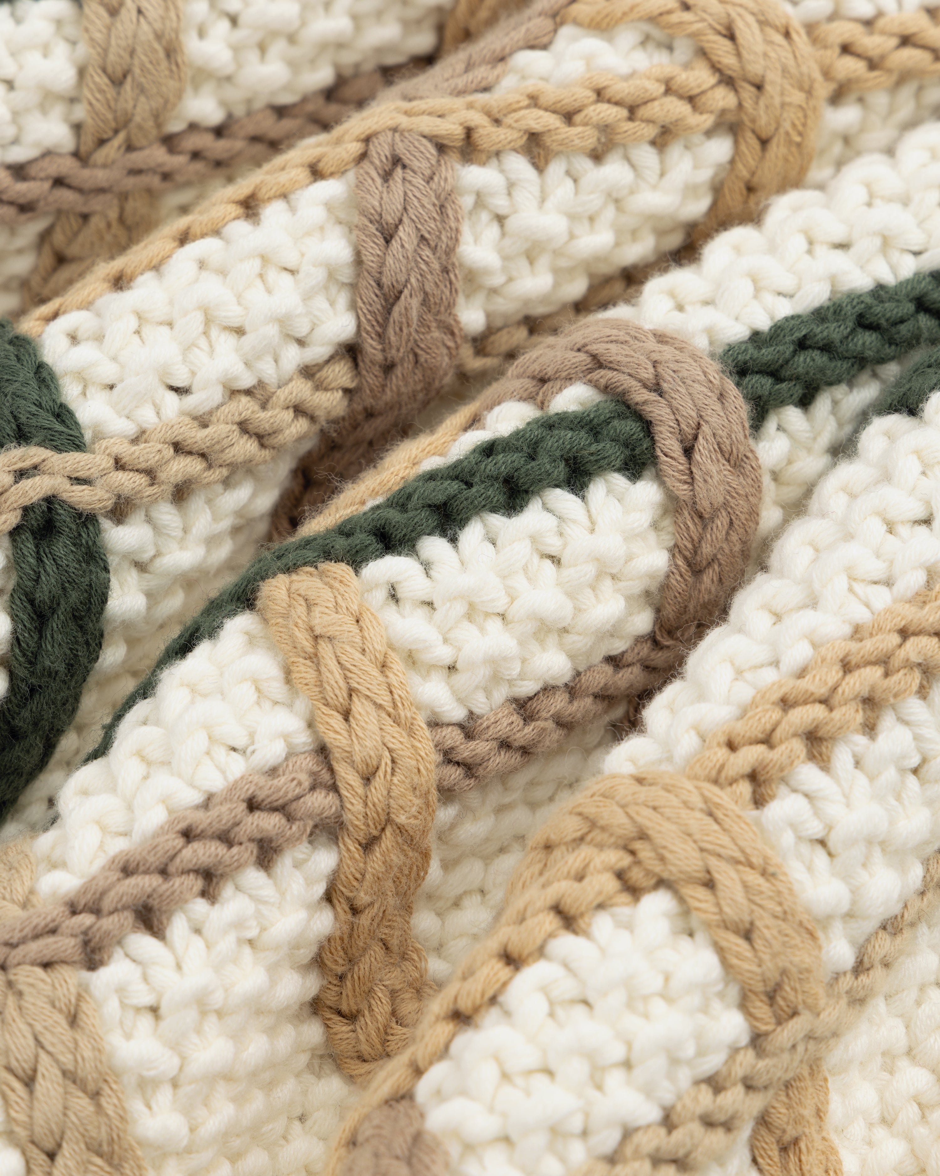 Close-up of a Cable Link Crewneck Sweater in a cream, tan, and dark green cable-stitch pattern.