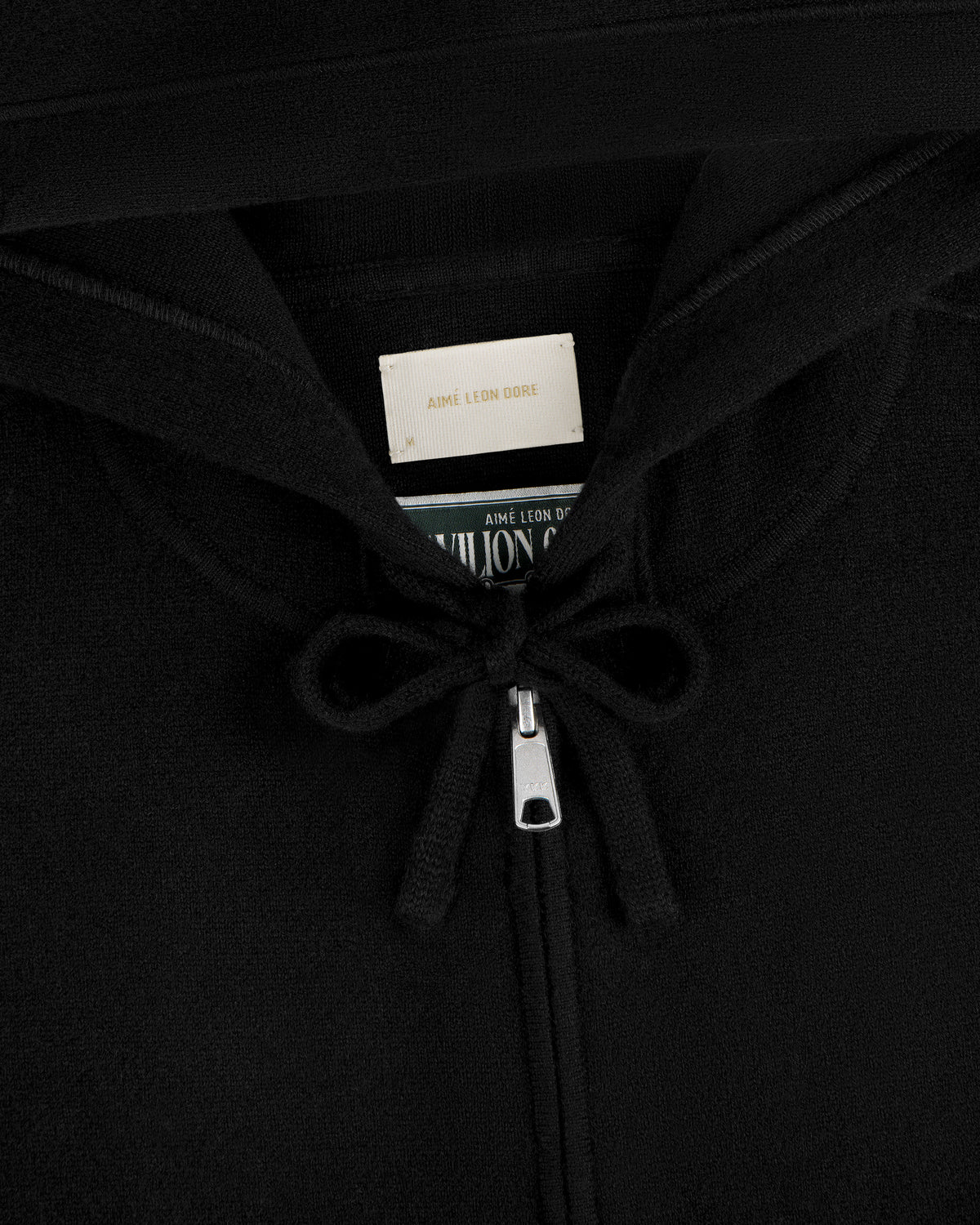 Close-up of Full-Zip Pavilion Cashmere Hoodie zipper with tied strings and label inside the collar.