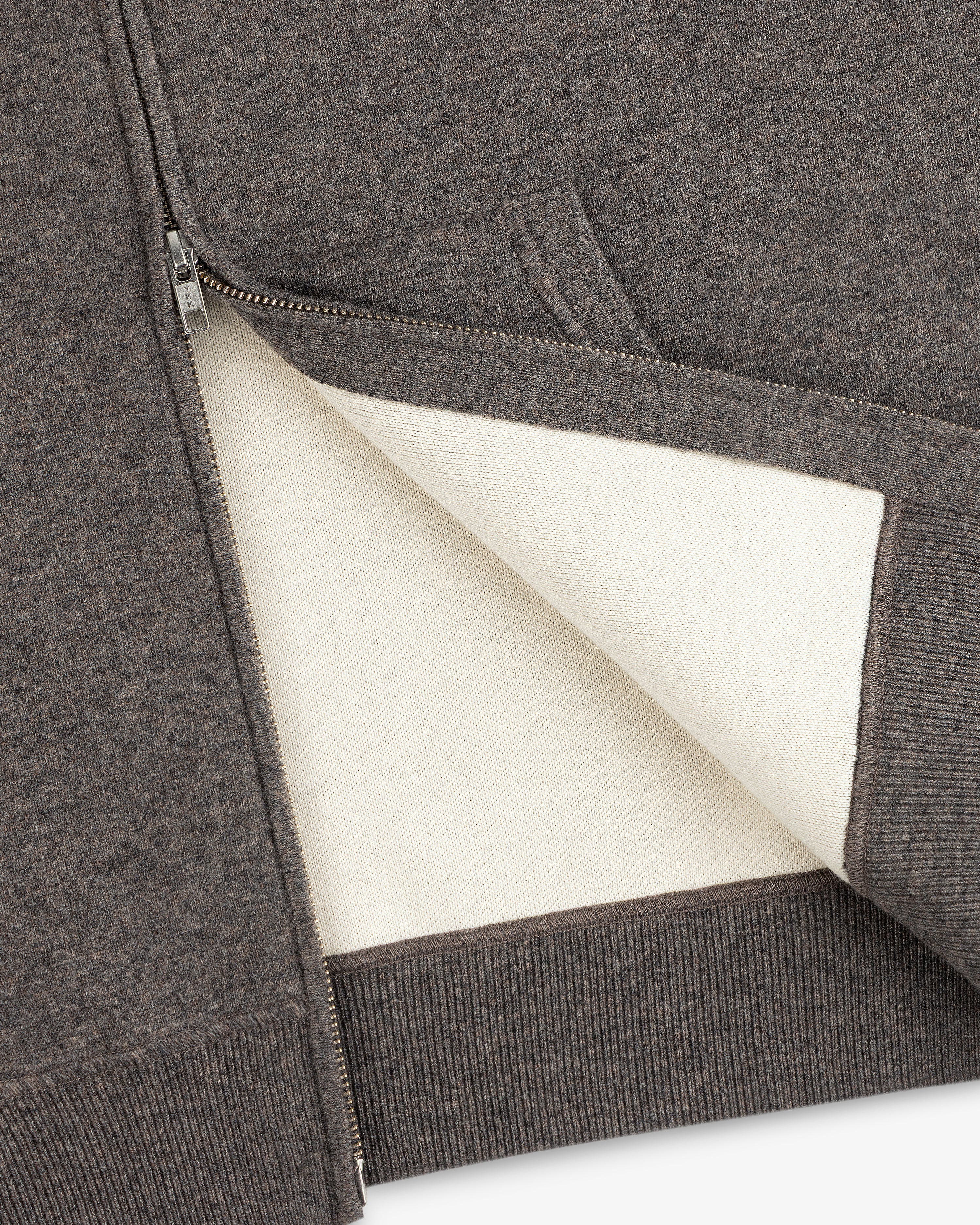 A close-up of the Full-Zip Pavilion Cashmere Hoodie, highlighting its off-white lining and ribbed hem.