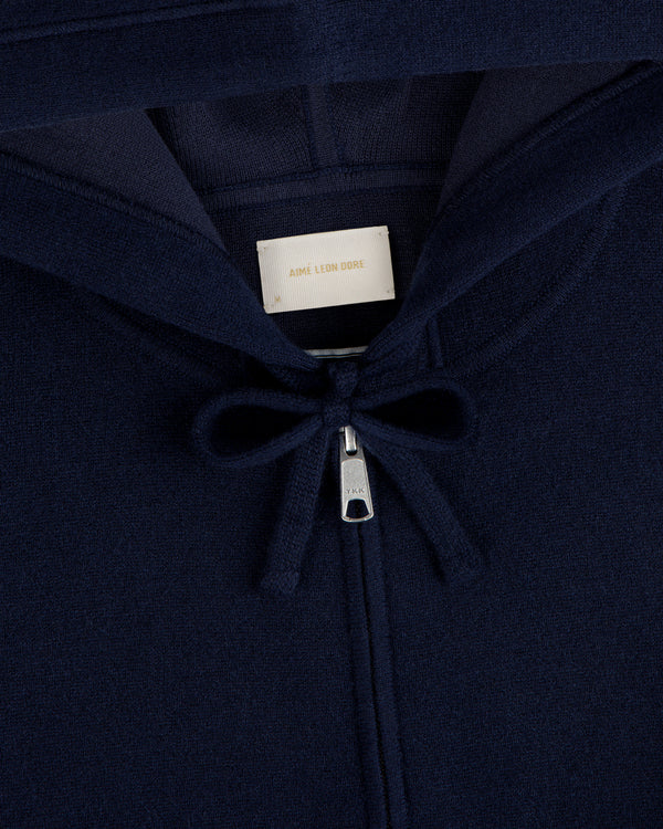 Close-up of the Full-Zip Pavilion Cashmere Hoodie in navy with zipper, drawstring, and Aimé Leon Dore collar label.