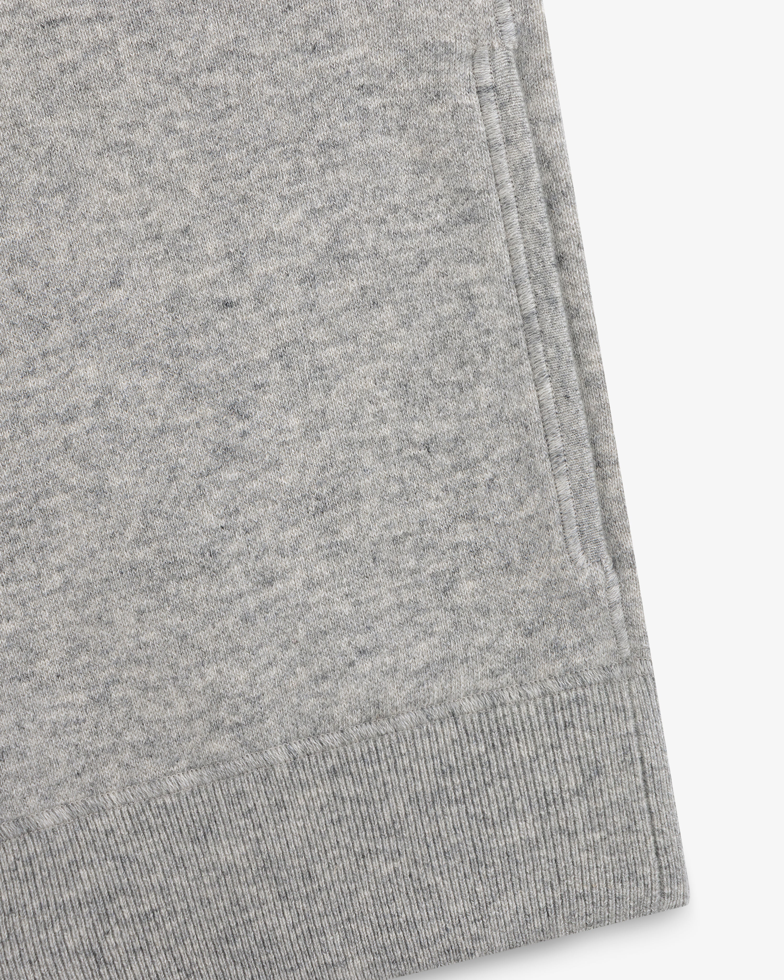 Close-up of a Quarter Zip Pavilion Cashmere Pullover hem and pocket in light gray on a white background.