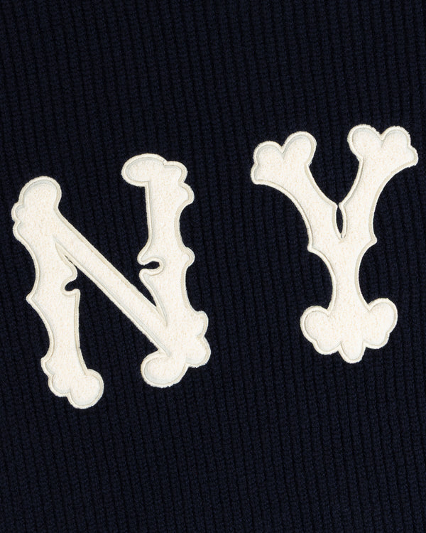 White ornate N and Y letters on a dark NY Highlanders Ribbed Wool Crewneck Sweater, resembling a monogram.