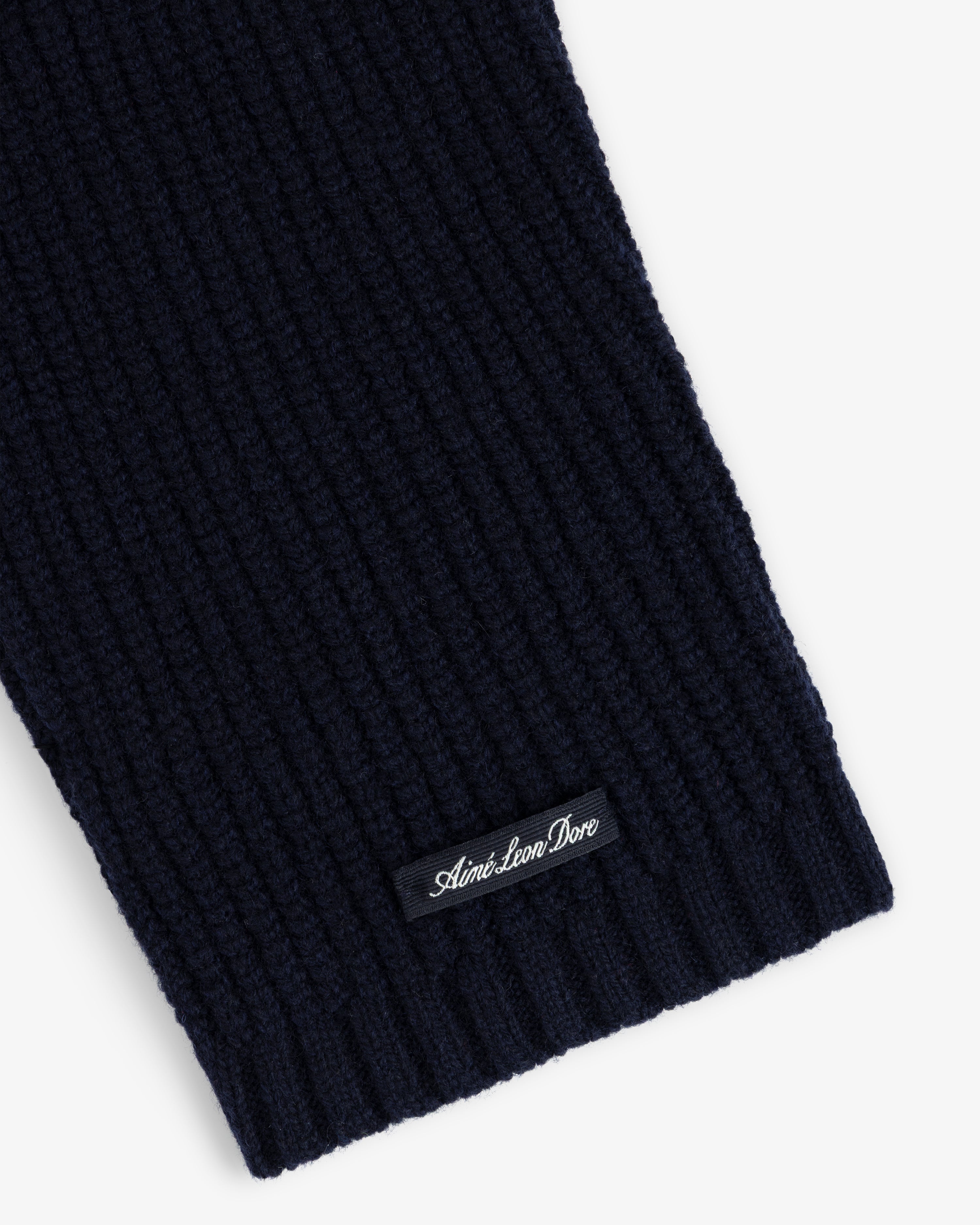 Close-up of a navy NY Highlanders Ribbed Wool Crewneck Sweater with Aimé Leon Dore label sewn near the edge.