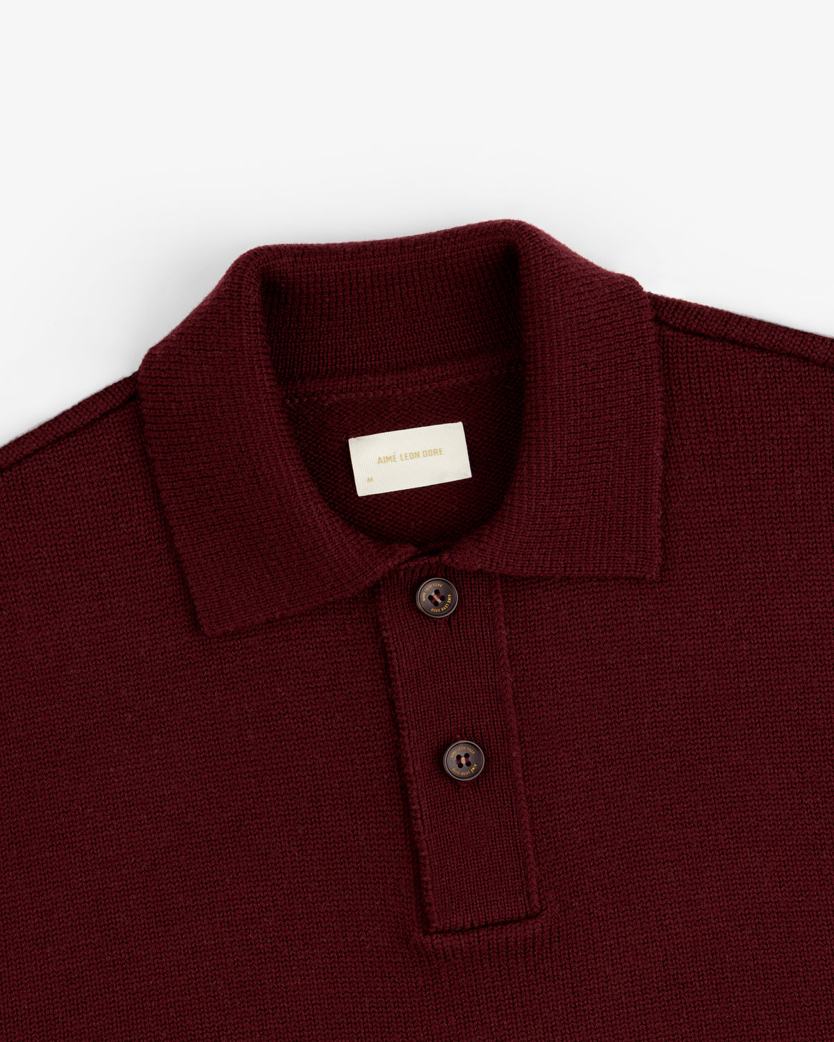 Close-up of a burgundy Long-Sleeve Merino Polo featuring a collar and two dark buttons.