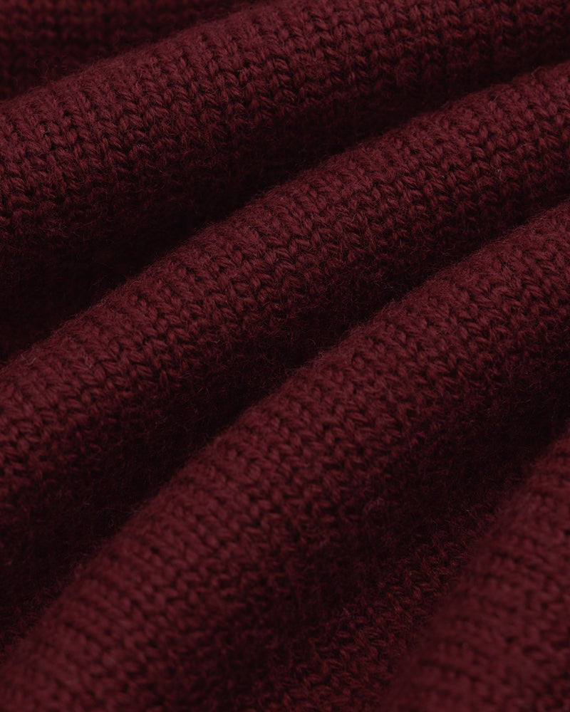 Close-up of folds in deep maroon knitted fabric of a Long-Sleeve Merino Polo.