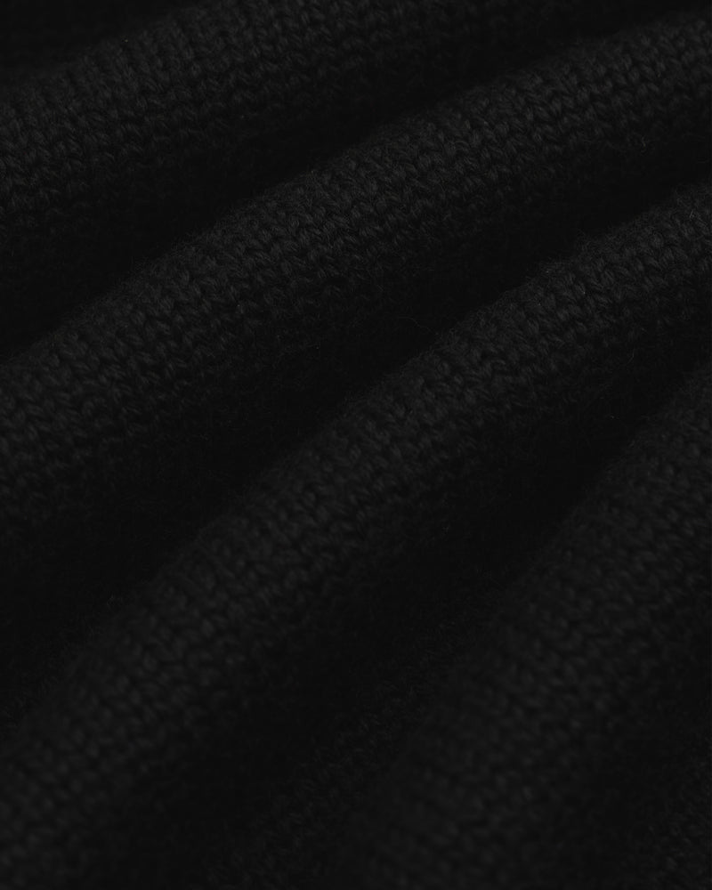 Close-up of black knit fabric from a Long-Sleeve Merino Polo with visible horizontal folds.