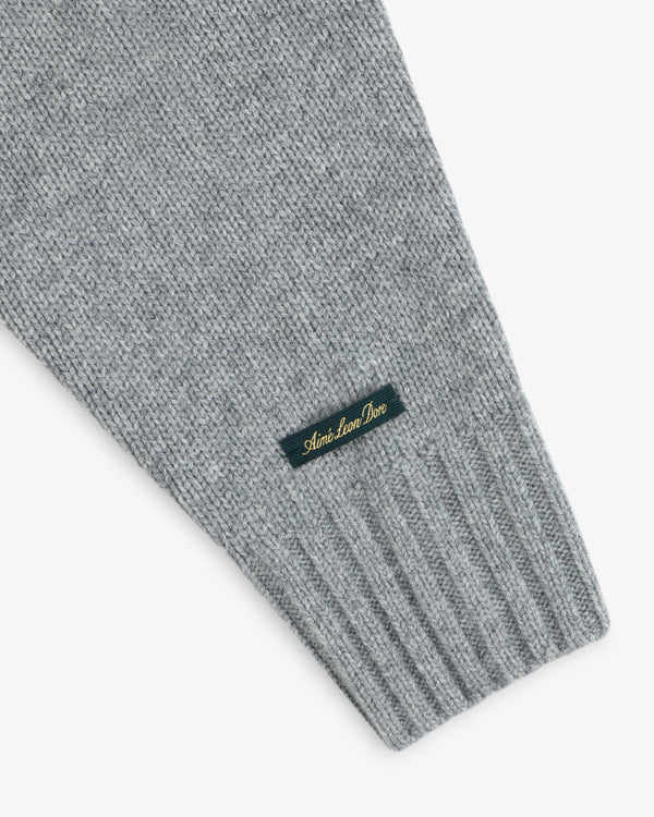 Grey Cashmere Crewneck Sweater sleeve with a ribbed cuff and a small woven tag featuring gold cursive text.