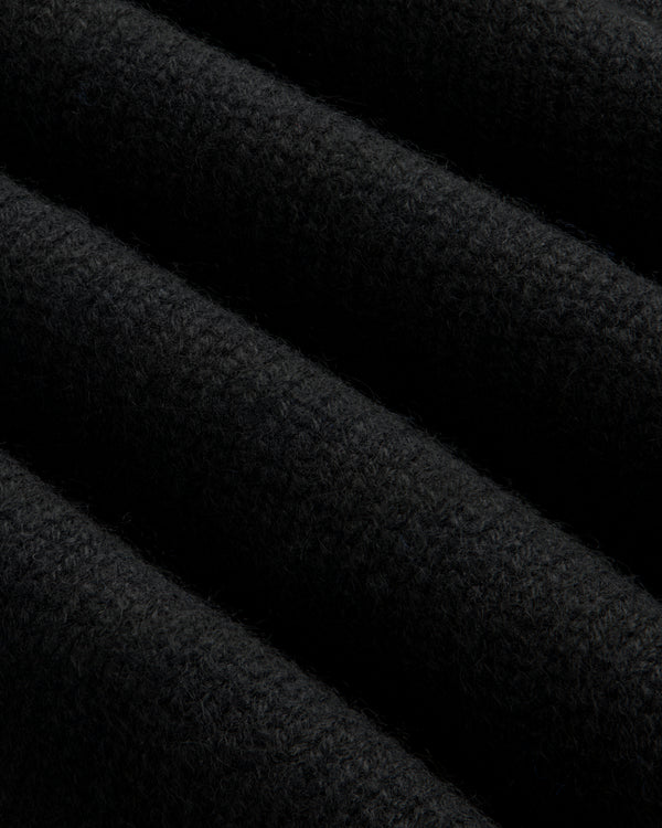 Close-up of a black Cashmere Crewneck Sweater showing diagonal folds in the knit fabric.