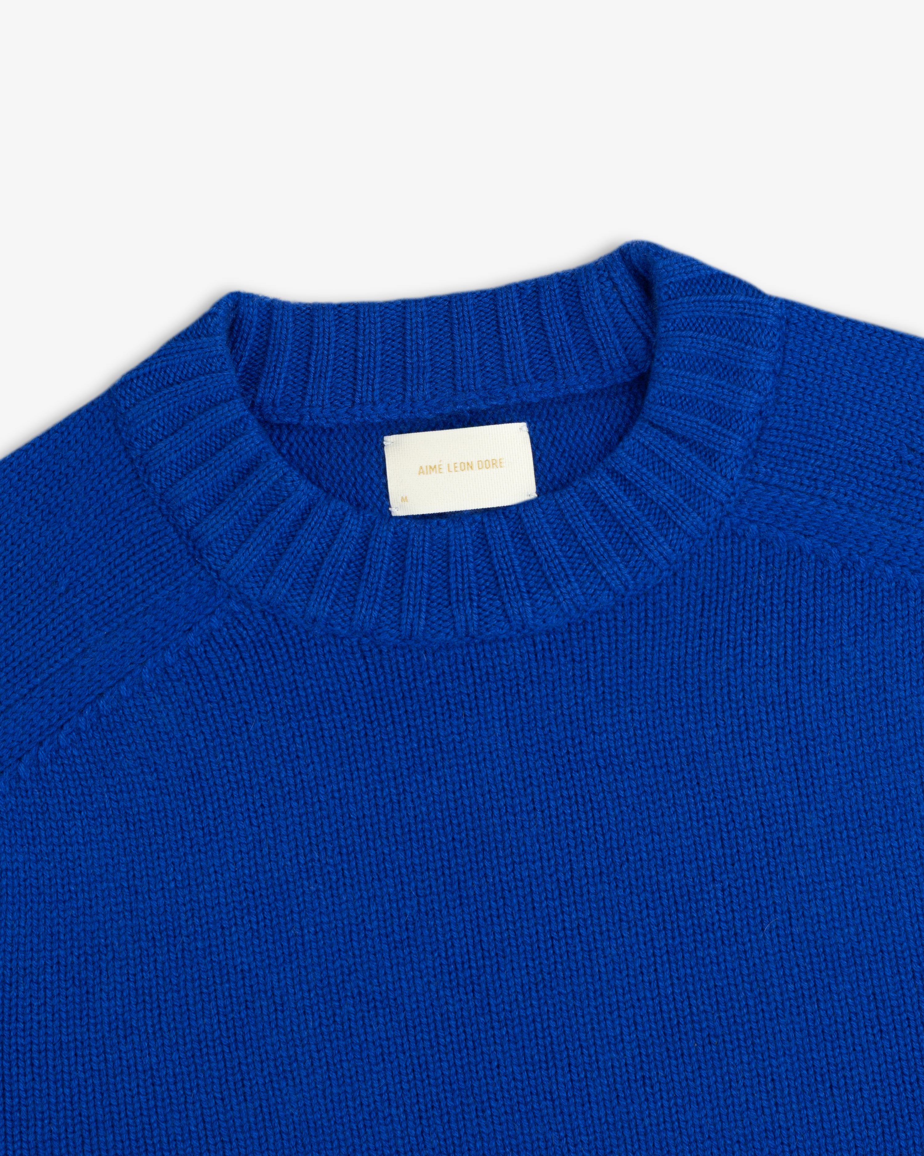 Close-up of a royal blue Cashmere Crewneck Sweater with a ribbed collar and an interior brand label.