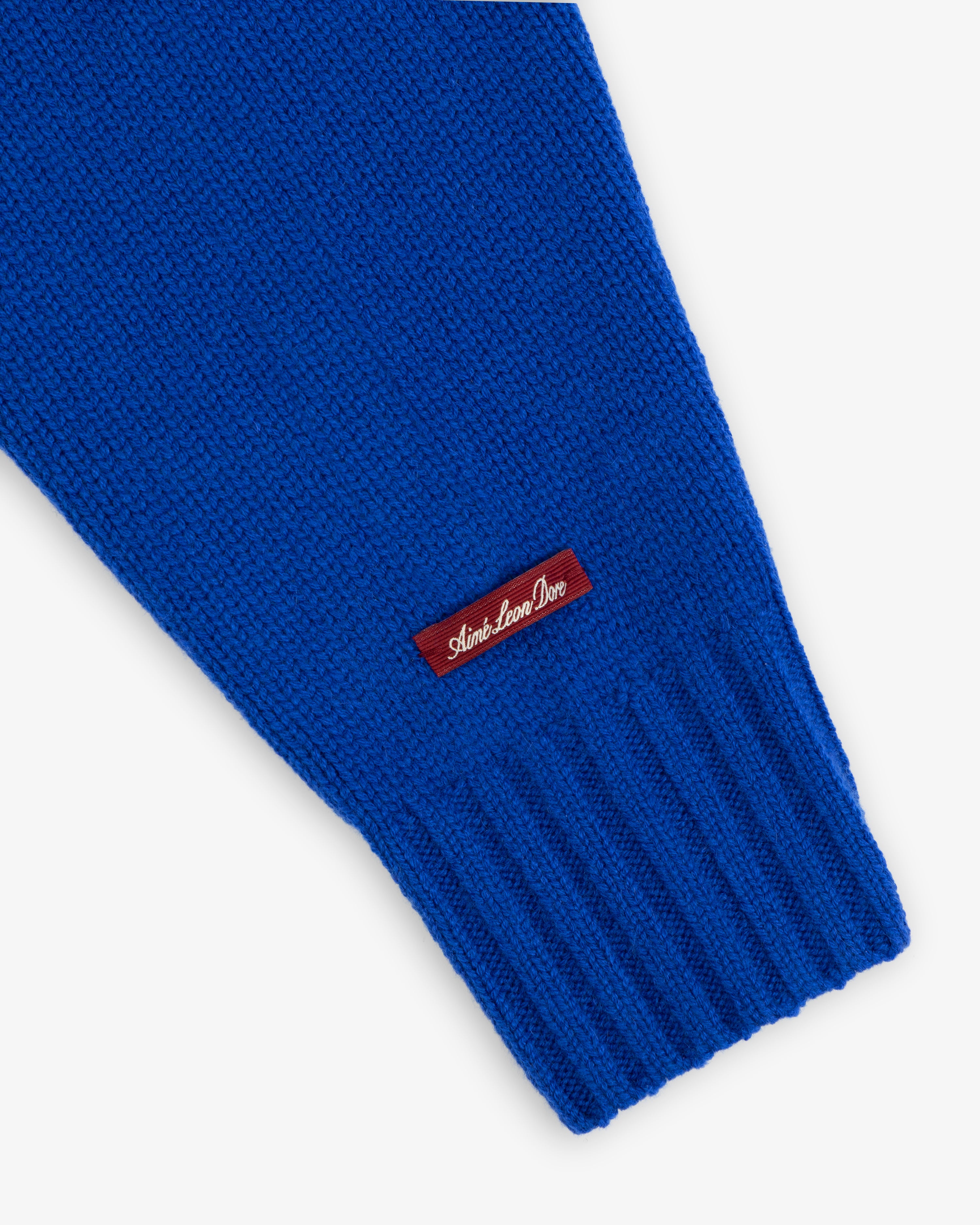 Bright blue Cashmere Crewneck Sweater sleeve featuring a ribbed cuff and a small rectangular logo tag.