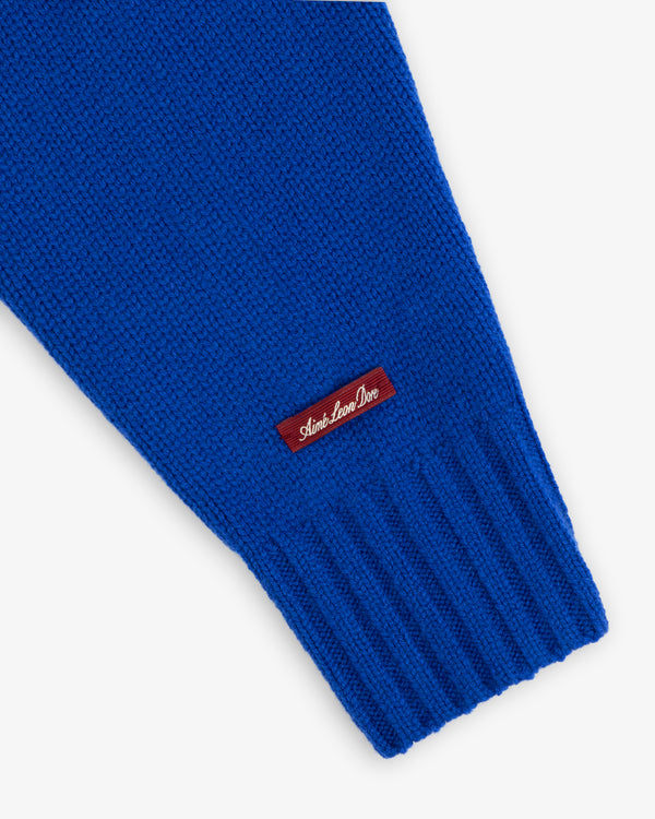 Bright blue Cashmere Crewneck Sweater sleeve featuring a ribbed cuff and a small rectangular logo tag.