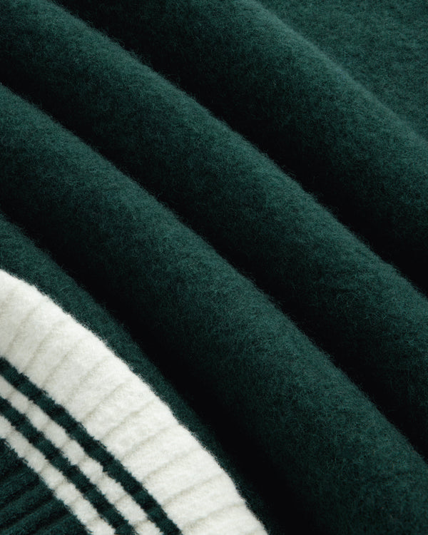 Boiled Wool Letterman Sweater in dark green felted wool with a white ribbed hem featuring two dark green stripes.