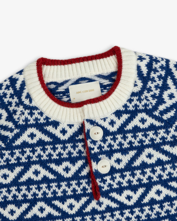 Poros Jacquard Pullover in a blue and white knit pattern with a red-trimmed collar and a two-button placket.